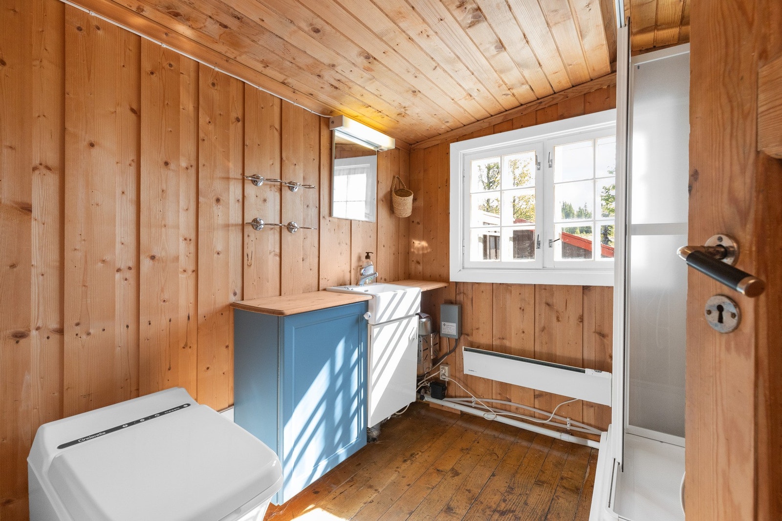Praktisk bad med adkomst fra kjøkkenet. Lakkerte tregulv og trepanel på vegger. Galleribilde