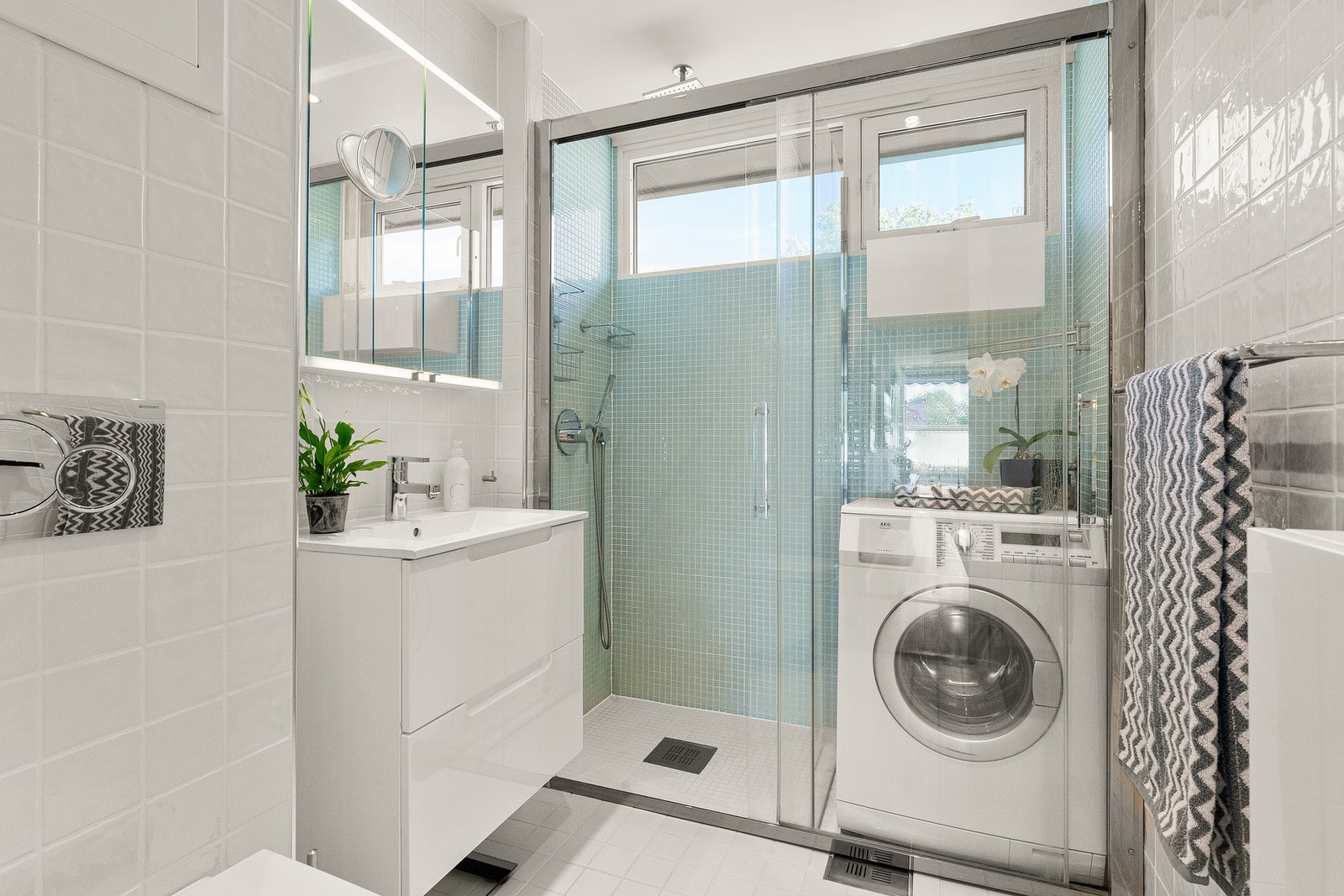 Baderommet ble oppusset i 2015 og fremstår med et tidløst preg, flislagt på både gulv og vegger. Regnfallsdusj innfelt i himling og praktisk nisje for vaskemaskin. Galleribilde