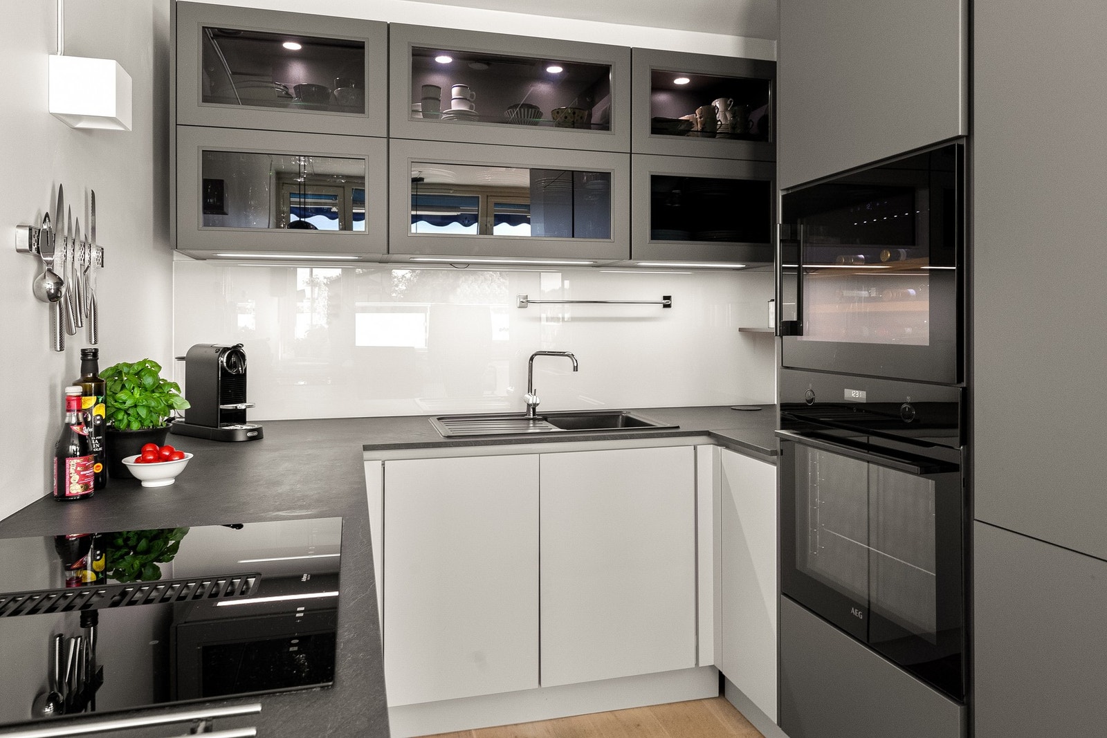 Alle hvitevarer er elegant integrert: induksjonstopp, stekeovn, oppvaskmaskin, vinskap og kombinert kjøleskap/fryser. Elegant glassplate er montert på veggen over induksjonstopp og vask. Galleribilde