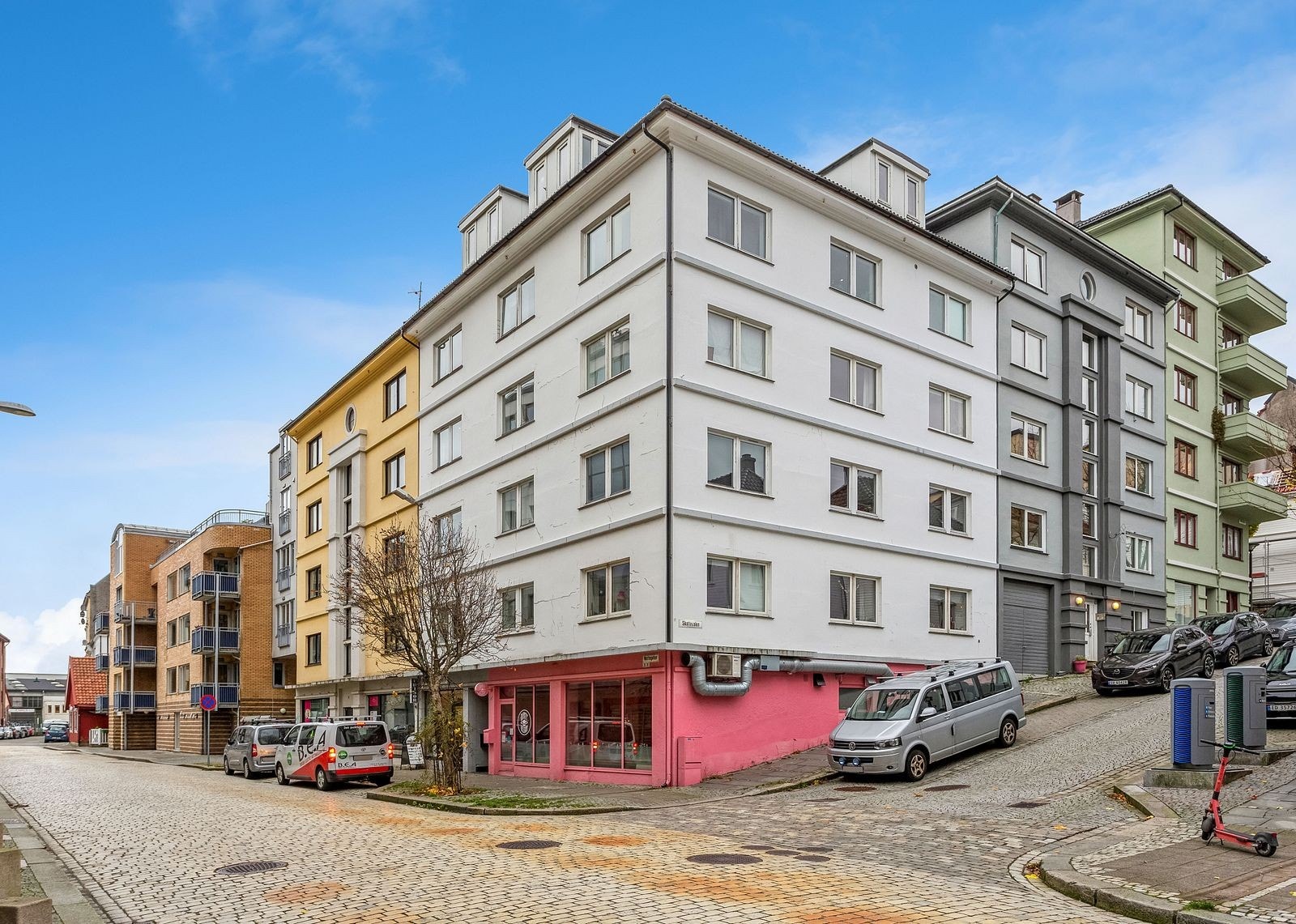 Leiligheten ligger over frisørsalongen til venstre (gult bygg), og blir betegnet som høy 1. etasje Galleribilde