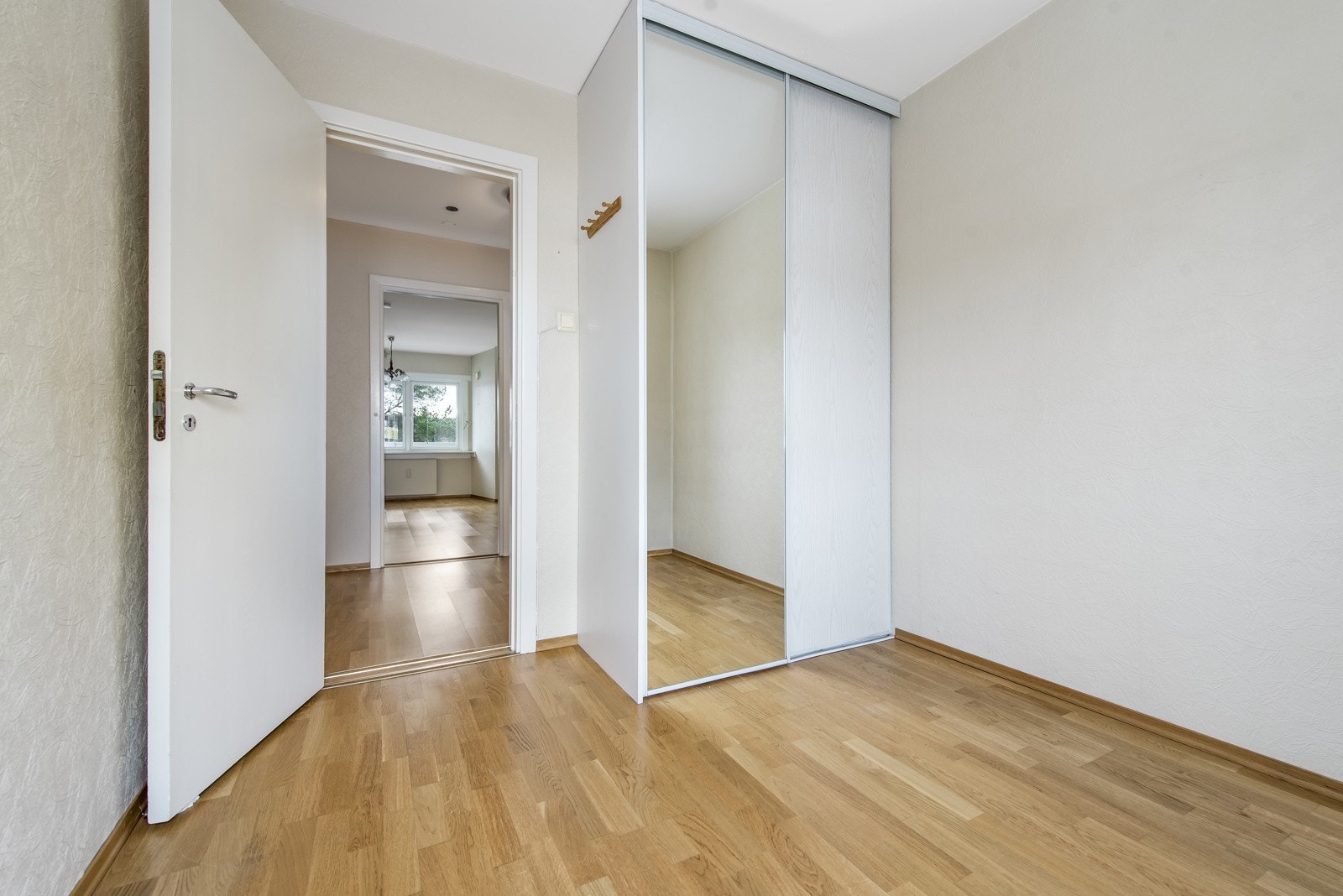 Soverom 2 med eik parkett på gulv og lyse vegger. Takhøyt garderobeskap. Galleribilde