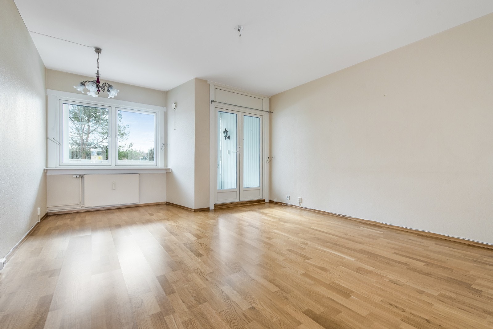 Stue med parkett på gulv, lyse malt vegger og utgang til balkong. Galleribilde