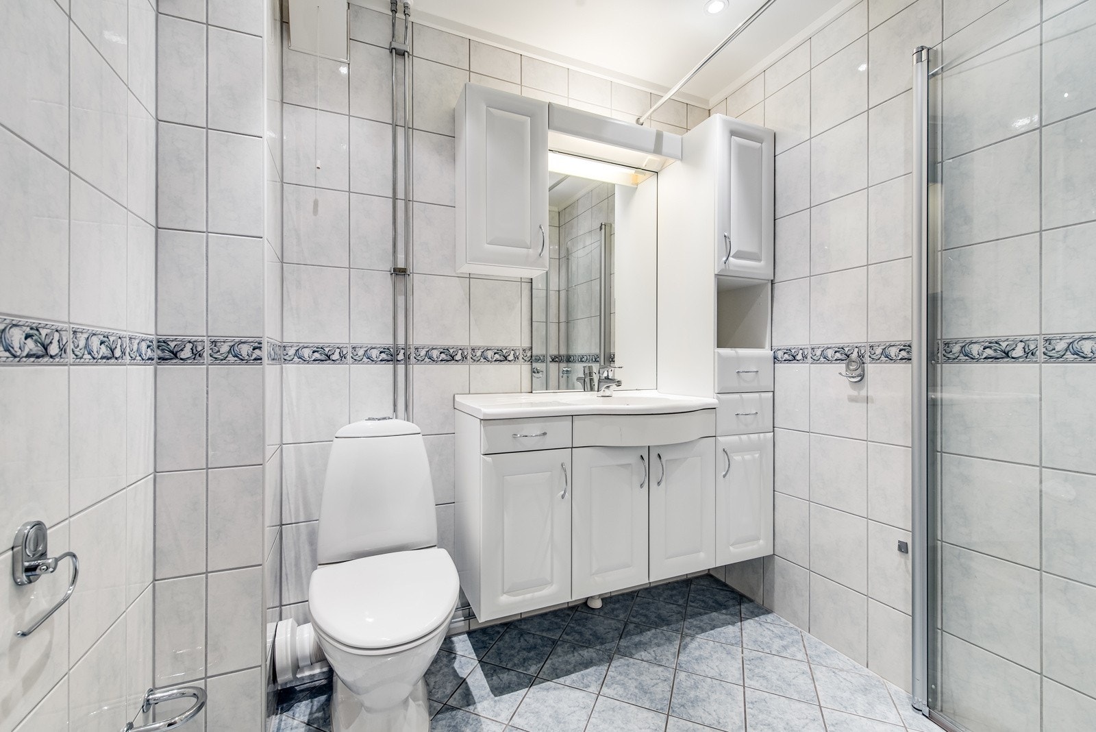 Rehabilitert bad, ferdigstilt i 2007. Varmekabler i gulv. Servant med innredning, toalett og dusj med innadslående dører. Galleribilde