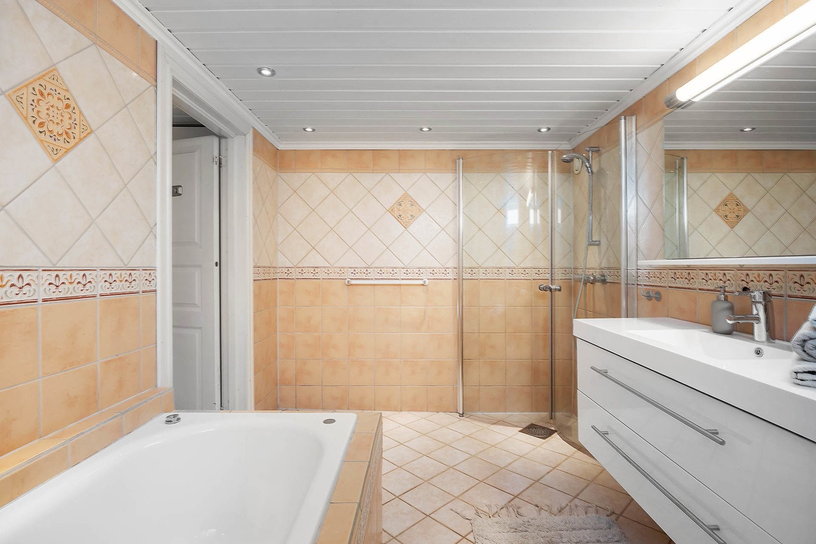 Varmekabler i gulv og downlights i himling. Heldekkende servant med skuffeseksjon under og speil med lys over. Galleribilde