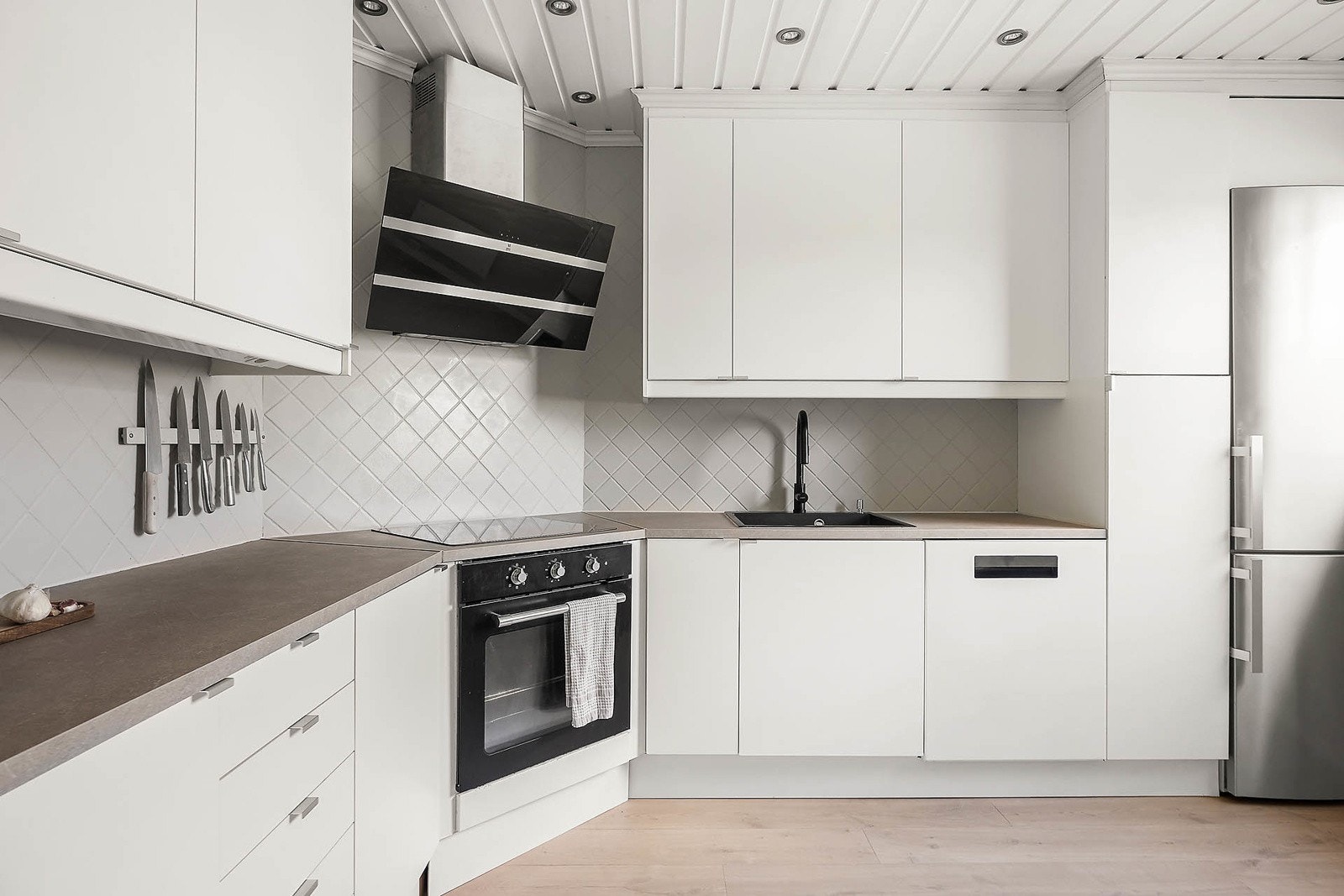 Kjøkken med ny benkeplate (2025) og integrert oppvaskmaskin, ovn og platetopp. Ventlatorhette i stål. Galleribilde