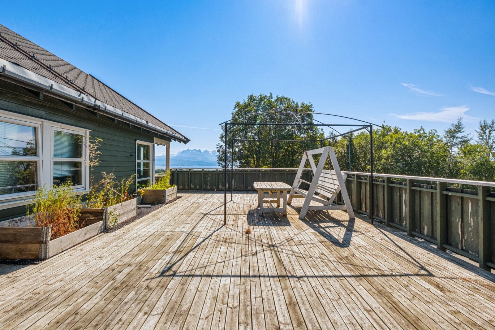 Her ute får du en sjelden kombinasjon av fjellpanorama, dyrkingskasser og full solbane - alt på én og samme flate. Galleribilde