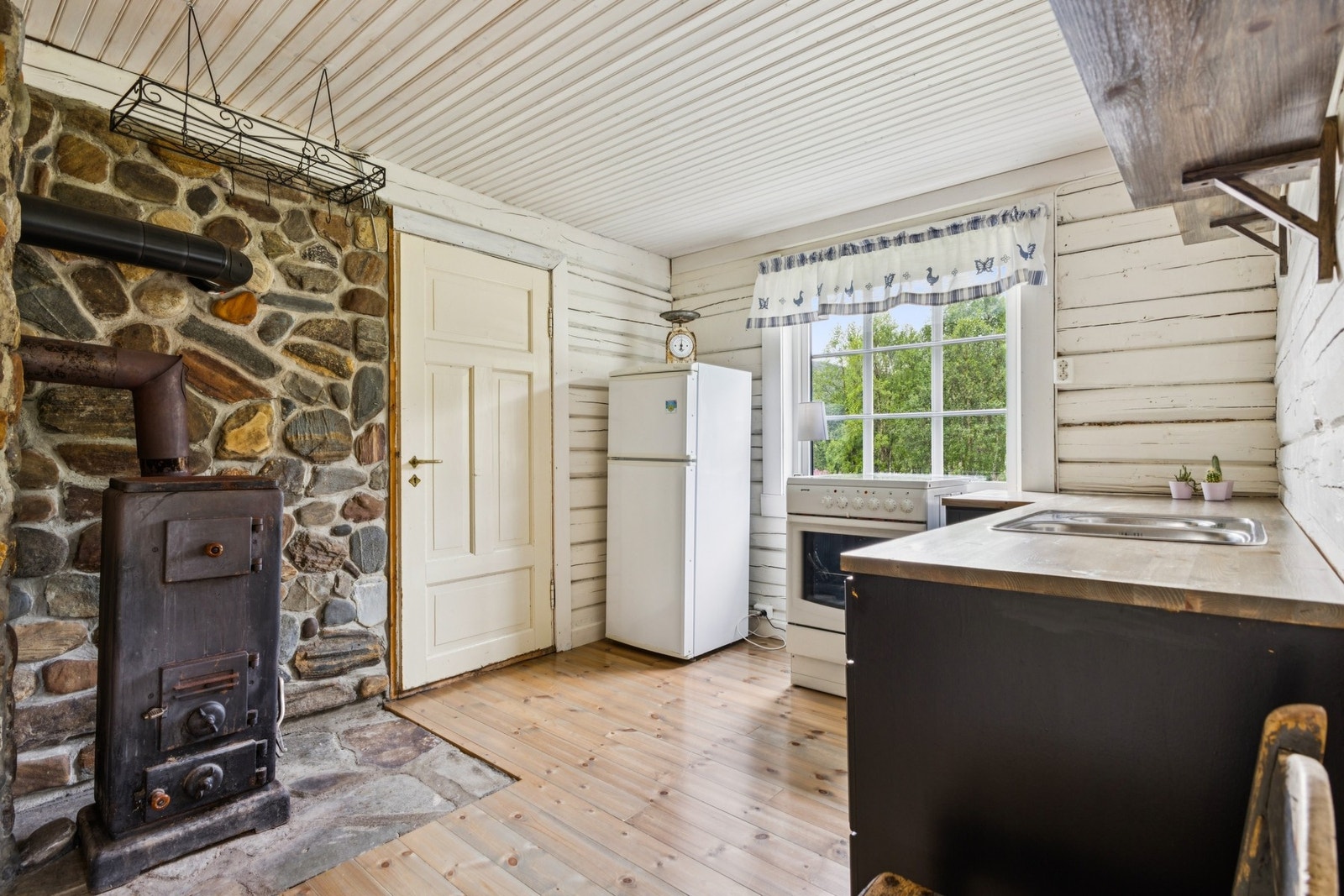 Enkelt og funksjonelt kjøkken med innredning, komfyr og stekeovn med platetopp. Galleribilde