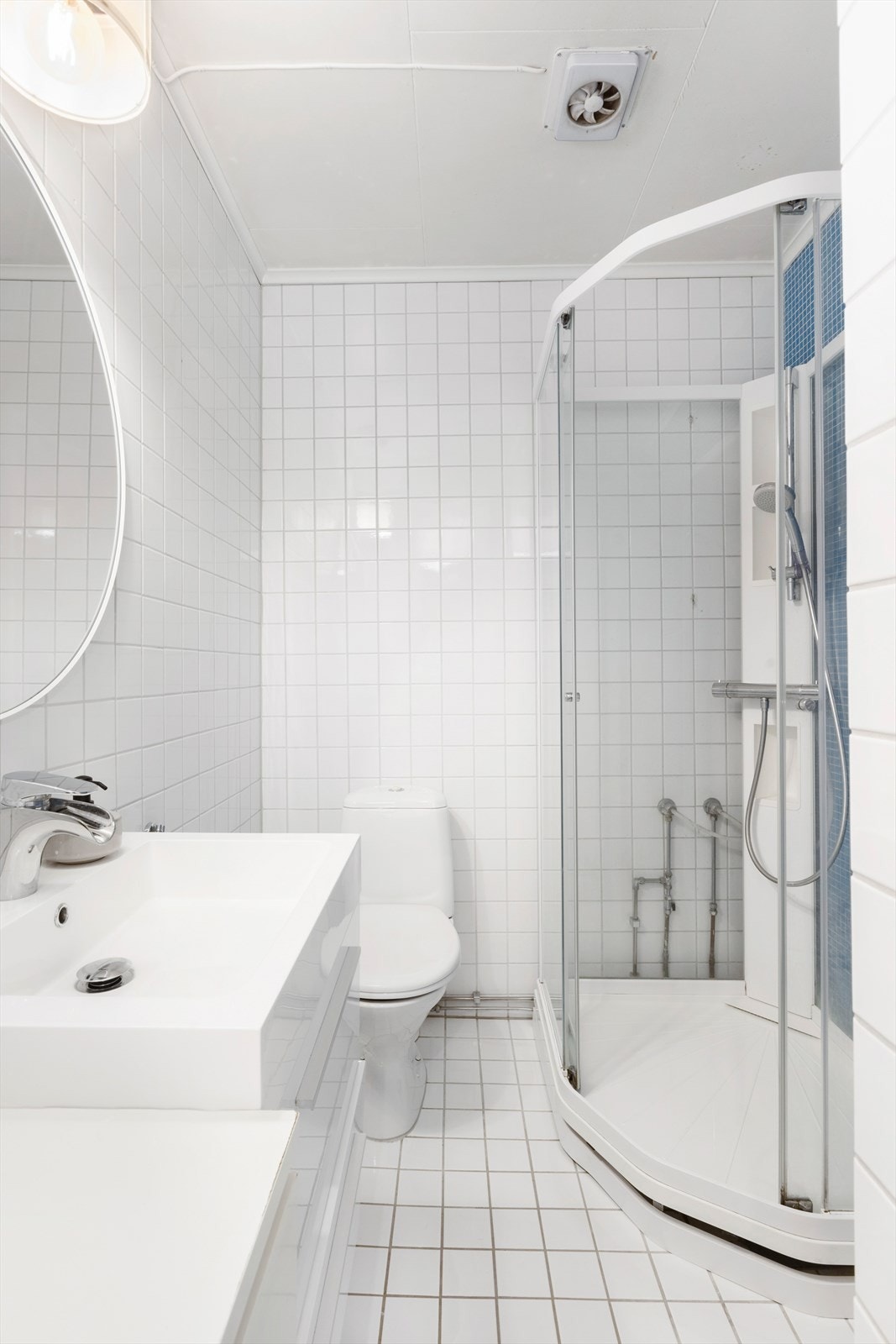 Lyst og pent flislagt bad med moderne innredning. Badet har dusjkabinett, toalett og servant med skuffer under for praktisk oppbevaring. Galleribilde