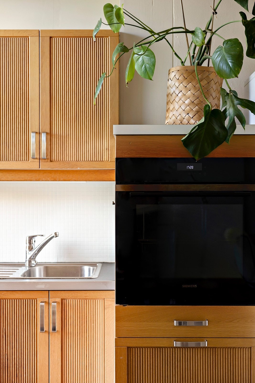 Kjøkkeninnredningen har elegante, heltre fronter med profil, og benkeplaten i laminat er utstyrt med nedfelt kum i rustfritt stål. Galleribilde