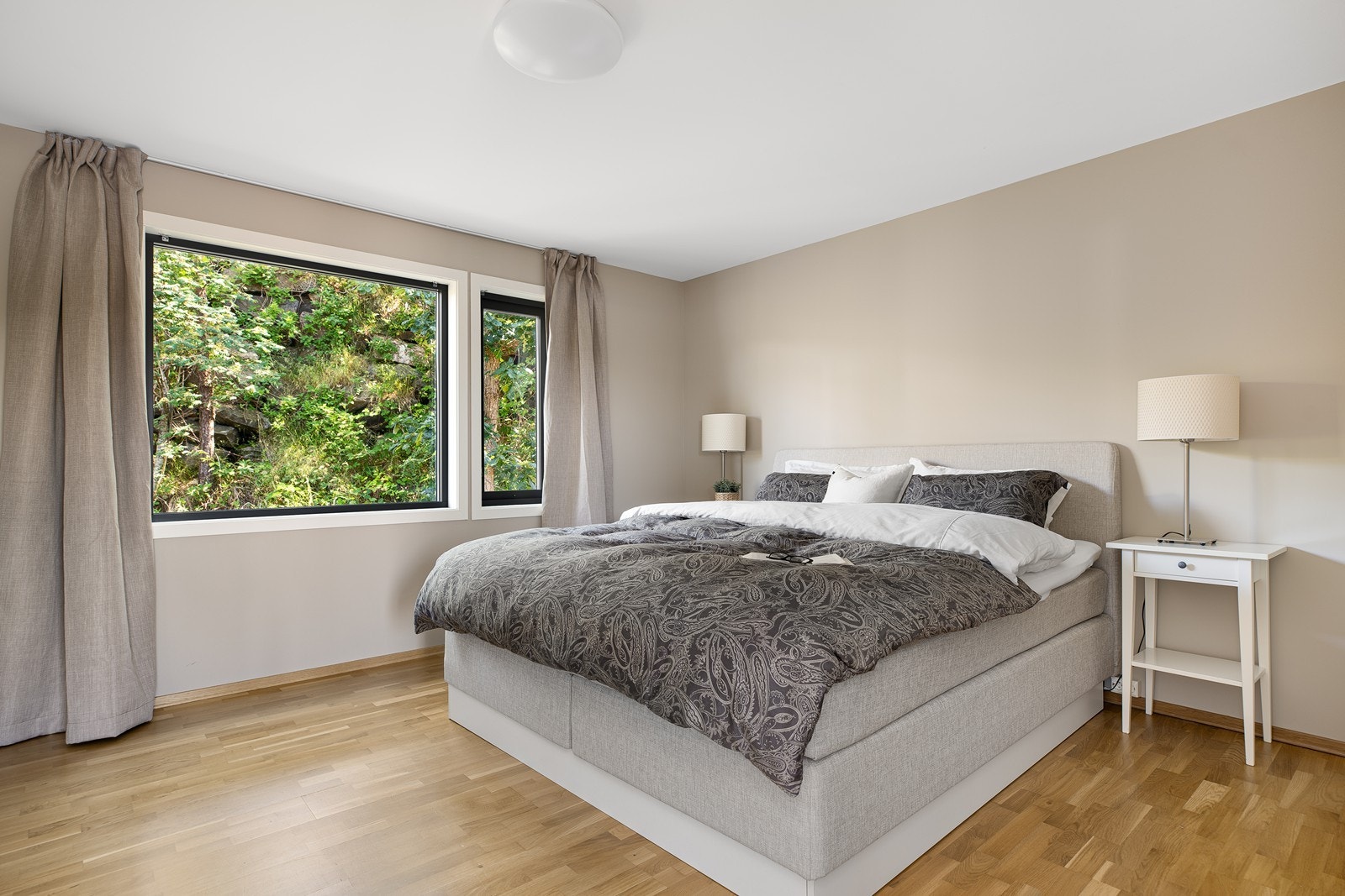 Romslig soverom med parkettgulv og moderne farger på veggene. Rommet er innredet med garderobeskap som gir godt med oppbevaringsplass Galleribilde