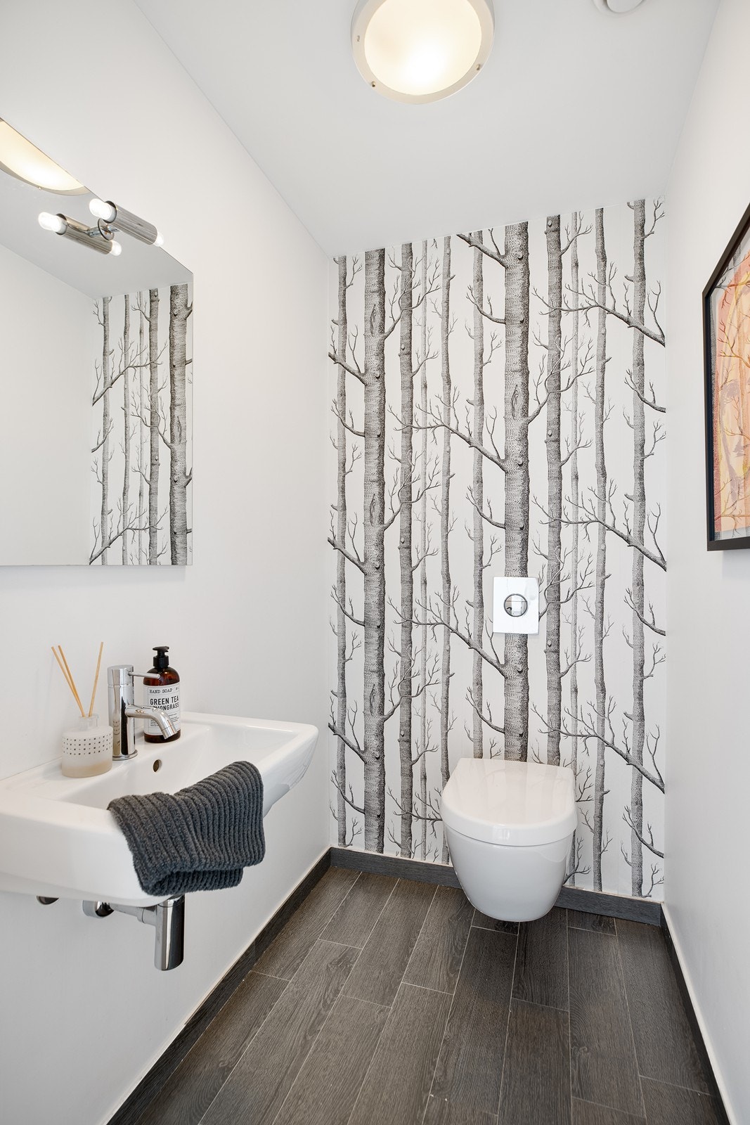 Lyst toalettrom med fliser på gulv. Innredet med vegghengt toalett og servant Galleribilde