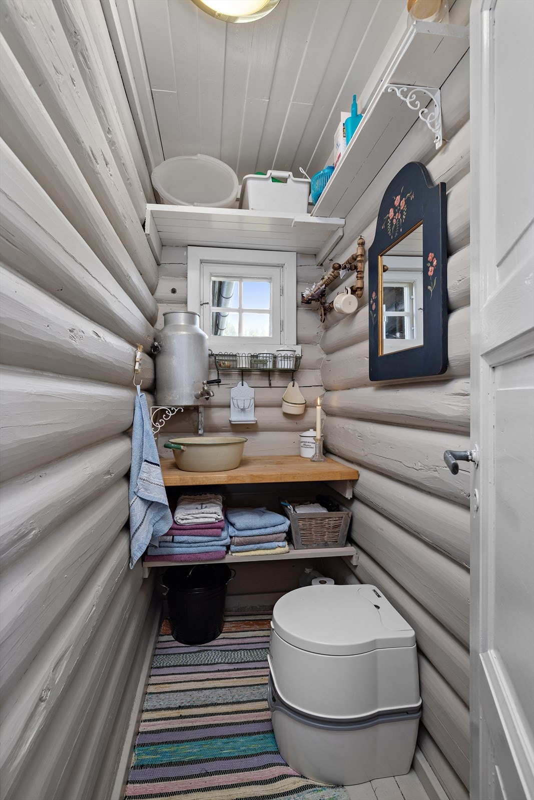 Et lite og enkelt vaskerom/stellerom med kjemisk toalett en skjenk og vaskevannsfat Galleribilde