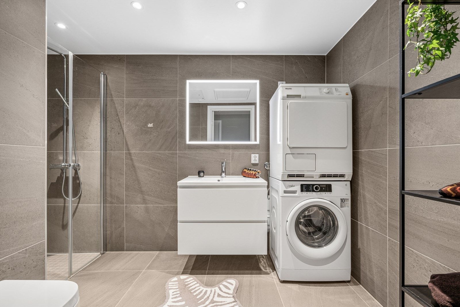 Baderommet fremstår som elegant og delikat, med tidsriktige farger, fliselagte vegger og gulv - en stilren og funksjonell oase med gjennomført kvalitet. Galleribilde