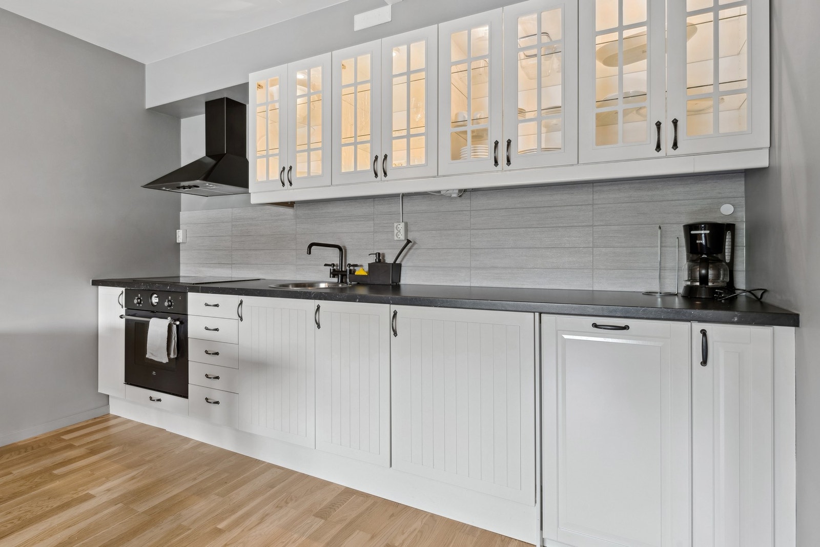 Lyst og moderne kjøkken med profilerte fronter. Kjøkkenet er utstyrt med integrert oppvaskmaskin, stekeovn, platetopp og kjøleskap. Galleribilde