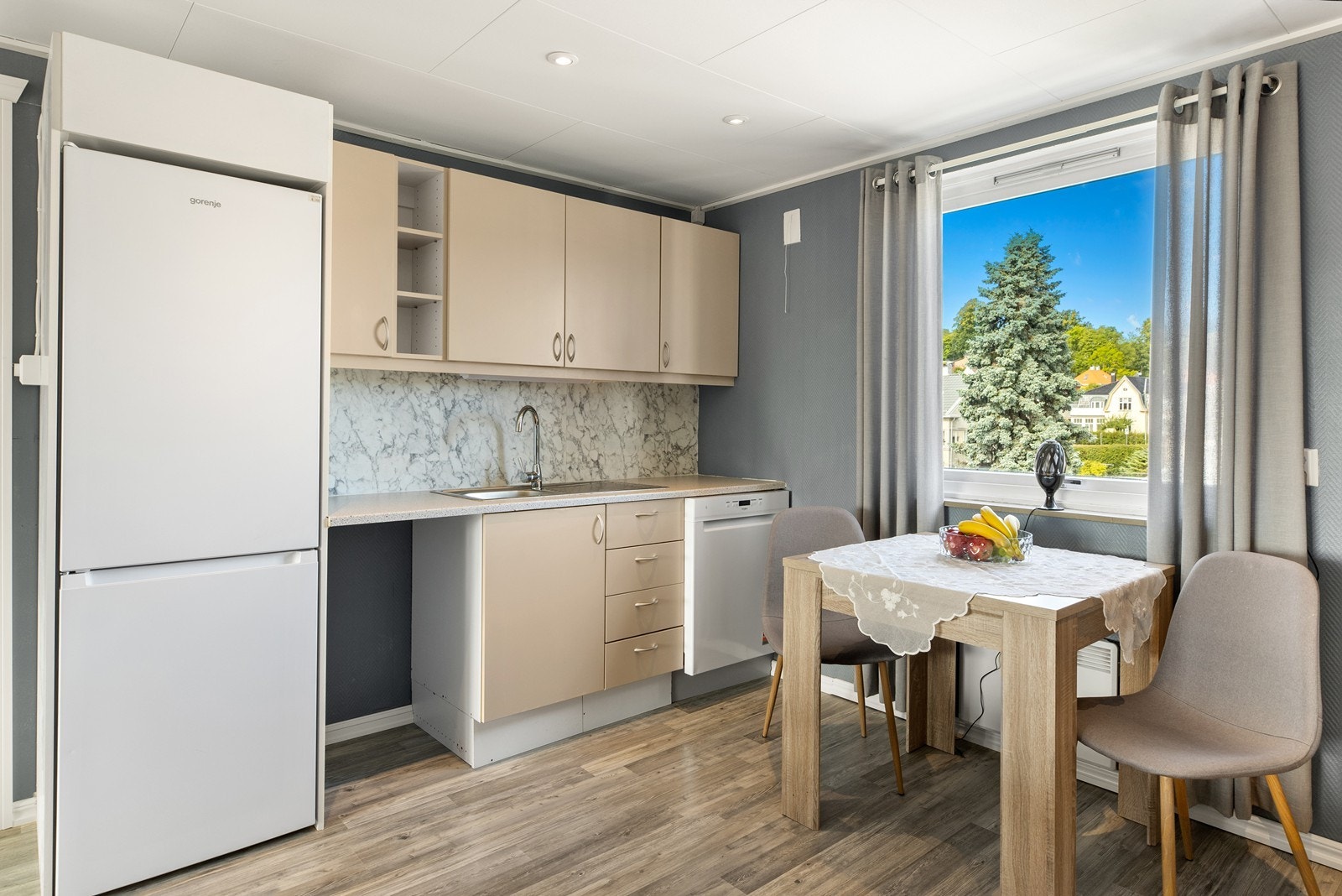 Her får du et praktisk og funksjonelt kjøkken med god arbeidsflate og plass til spisebord ved vinduet. Spotter i taket gir god belysning, og hvitevarer som medfølger - uten garanti utover eventuell leverandørgaranti. Galleribilde