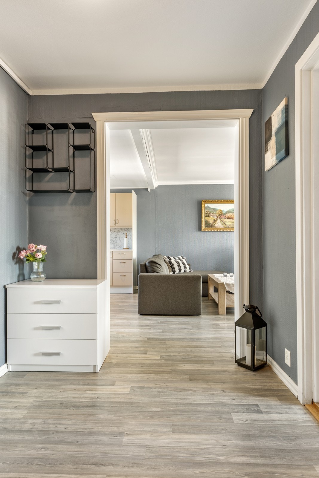 Lys og innbydende gang som binder boligen sammen på en praktisk og oversiktlig måte. Herfra har du tilgang til både soverom og bad, samt videre inn til boligens sosiale soner - stue og kjøkken. Galleribilde