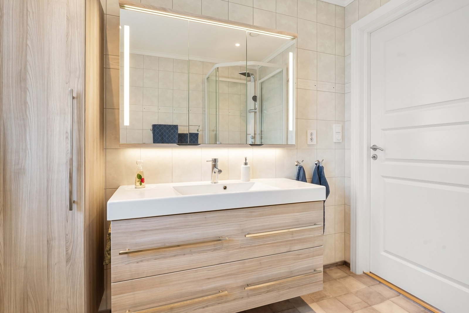 Romslig bad som er praktisk innredet. Legg merke til høyskapet og speilskapet. Galleribilde