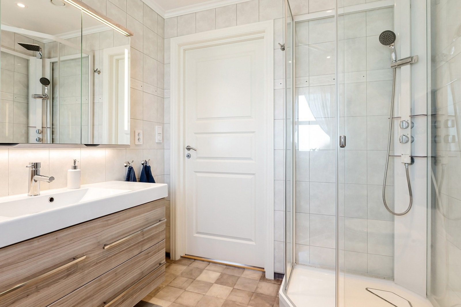 Romslig bad som er praktisk innredet. Legg merke til høyskapet og speilskapet. Galleribilde