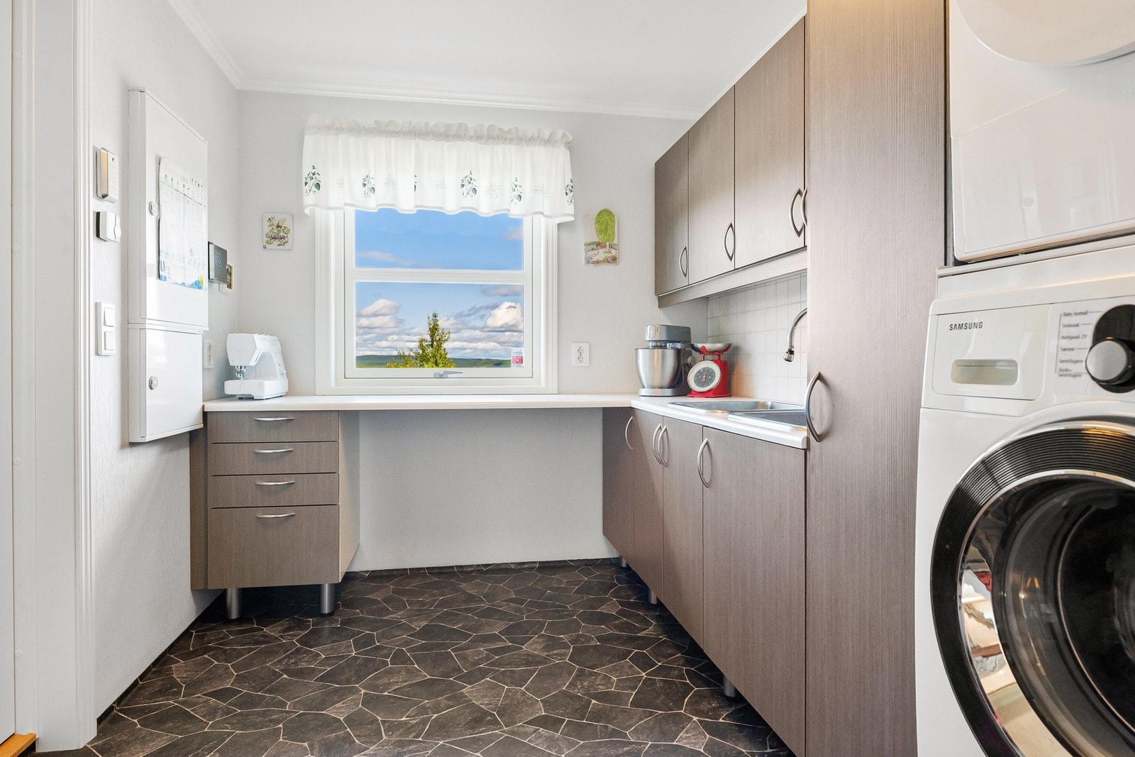 Godt, innredet vaskerom med utslagsvask, benkeplate og skap. Galleribilde