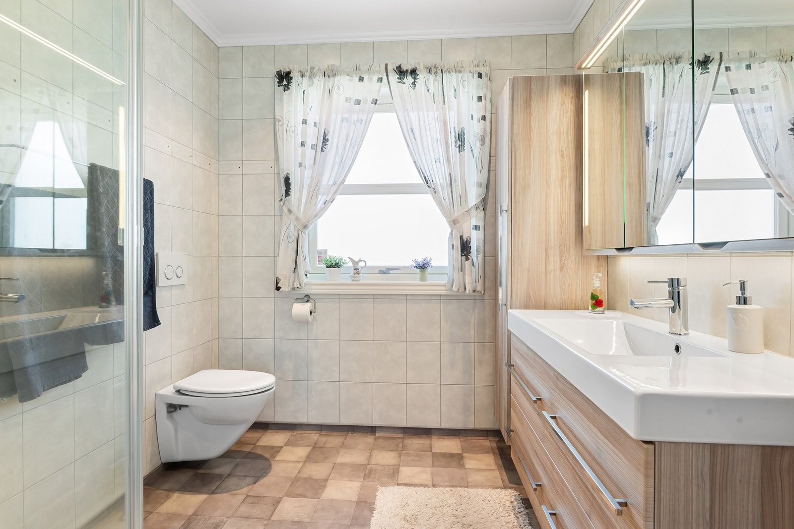 Romslig bad som er praktisk innredet. Legg merke til høyskapet og speilskapet. Galleribilde