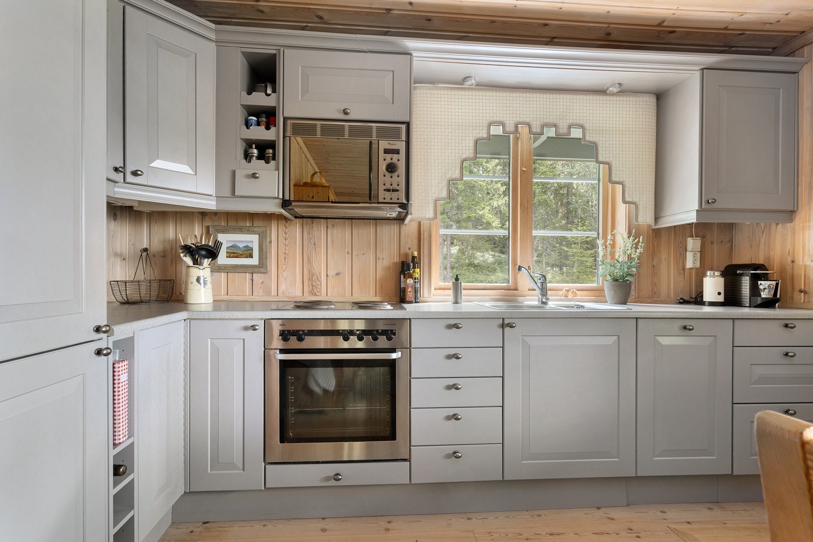 Praktisk kjøkkeninnredning med integrerte hvitevarer som komfyr, platetopp, micro, oppvaskmaskin og kjøl-/frys. Galleribilde