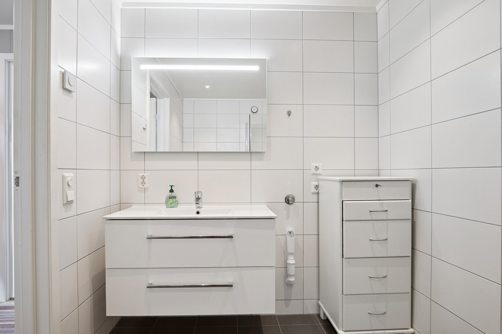 Baderomsinnredning med vegghengt servantskap, speil med belysning og gode oppbevaringsmuligheter. Galleribilde