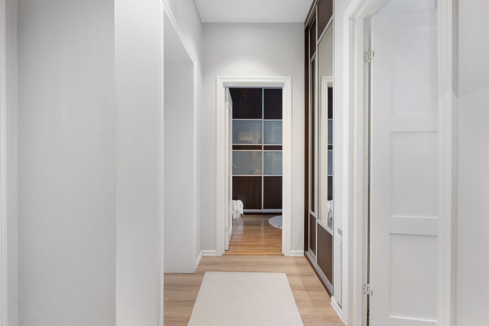 Velkommen inn i en lys og innbydende entré. Her finner du en praktisk garderobeløsning diskret plassert på høyre side innerst i gangen med skyvedører. Galleribilde