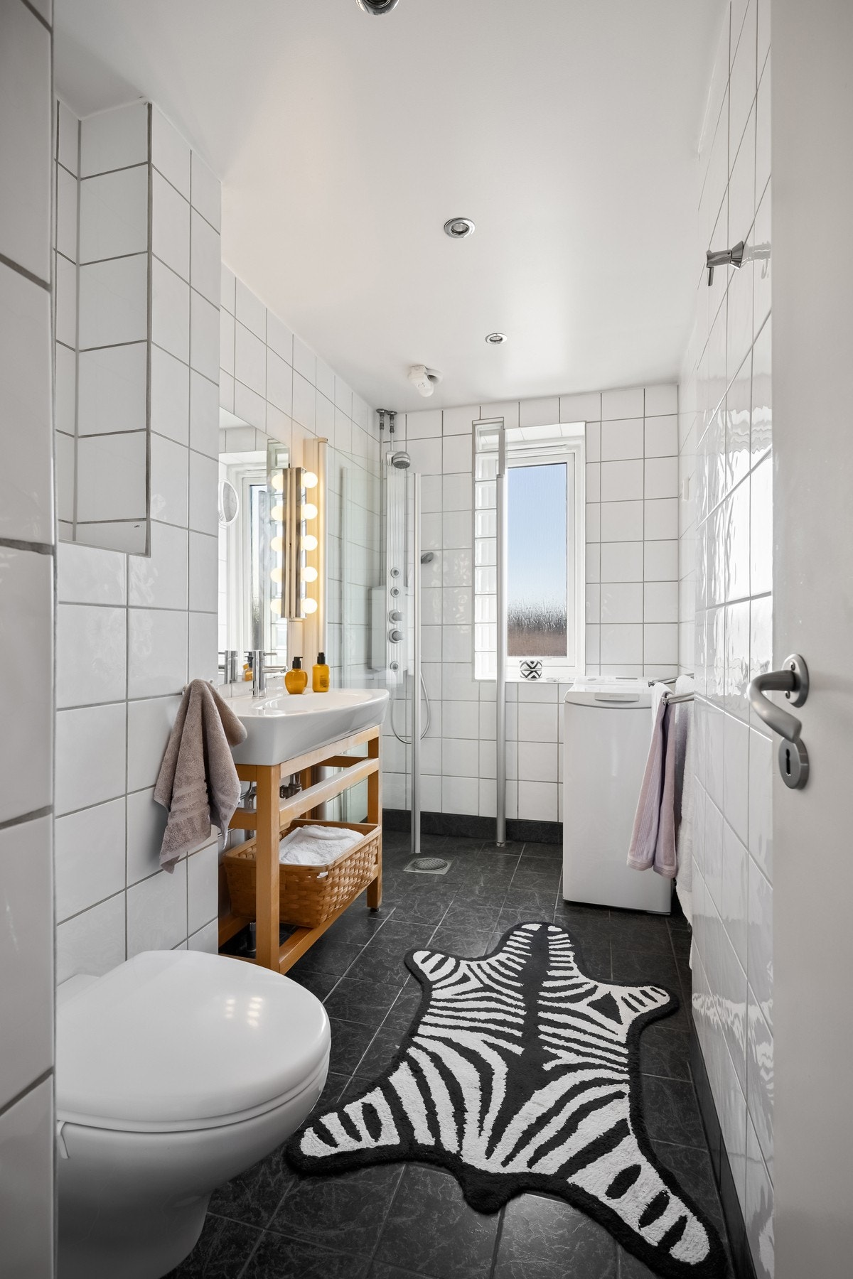 Flislagt bad med varme i gulv - Dusjhjørne, veggmontert toalett og opplegg for vaskemaskin Galleribilde