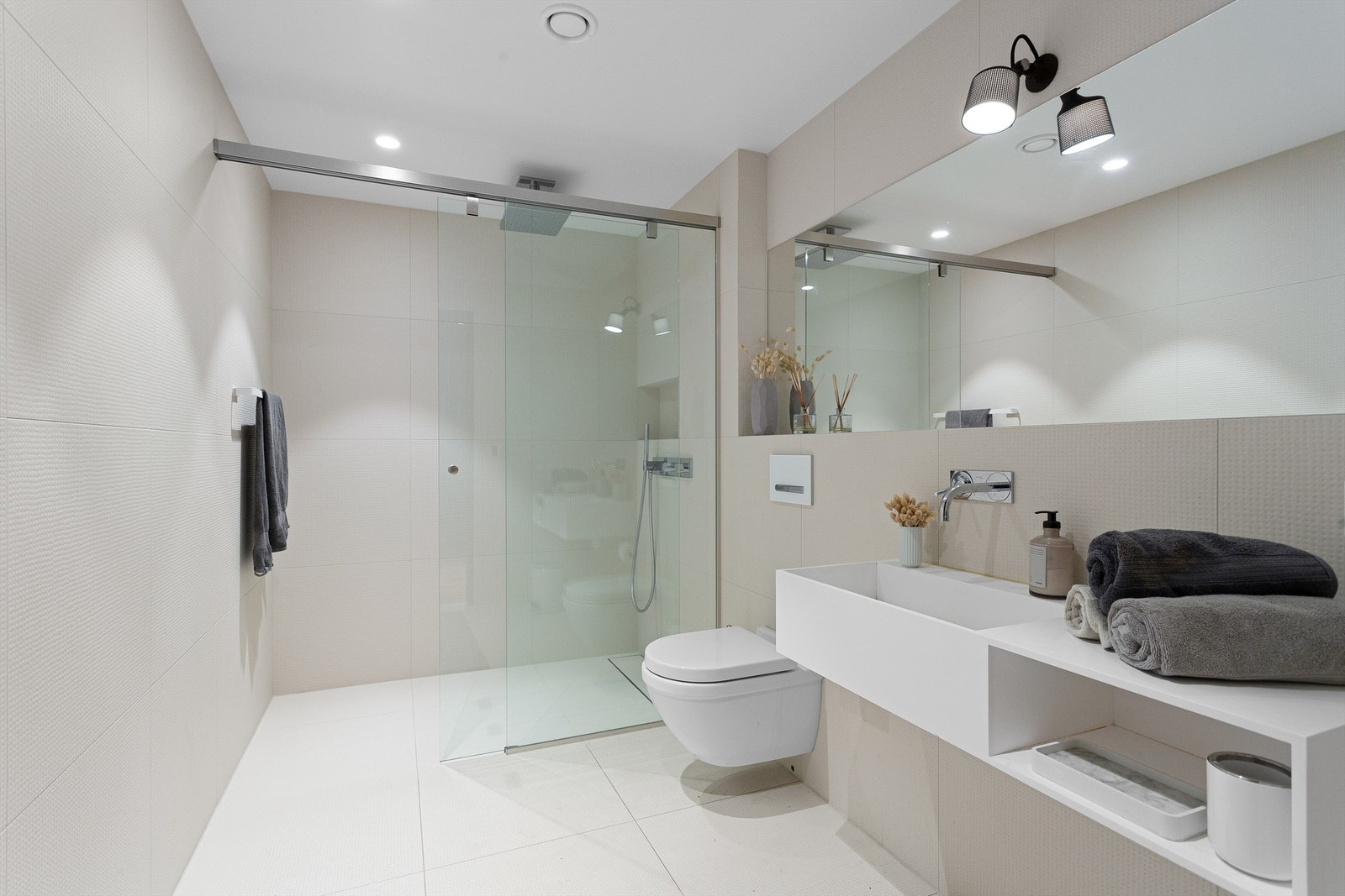 Bad 5 med dusjhjørne som har skyvbar dusjvegg av glass, veggmontert armatur og takmontert regnfallsdusj Galleribilde