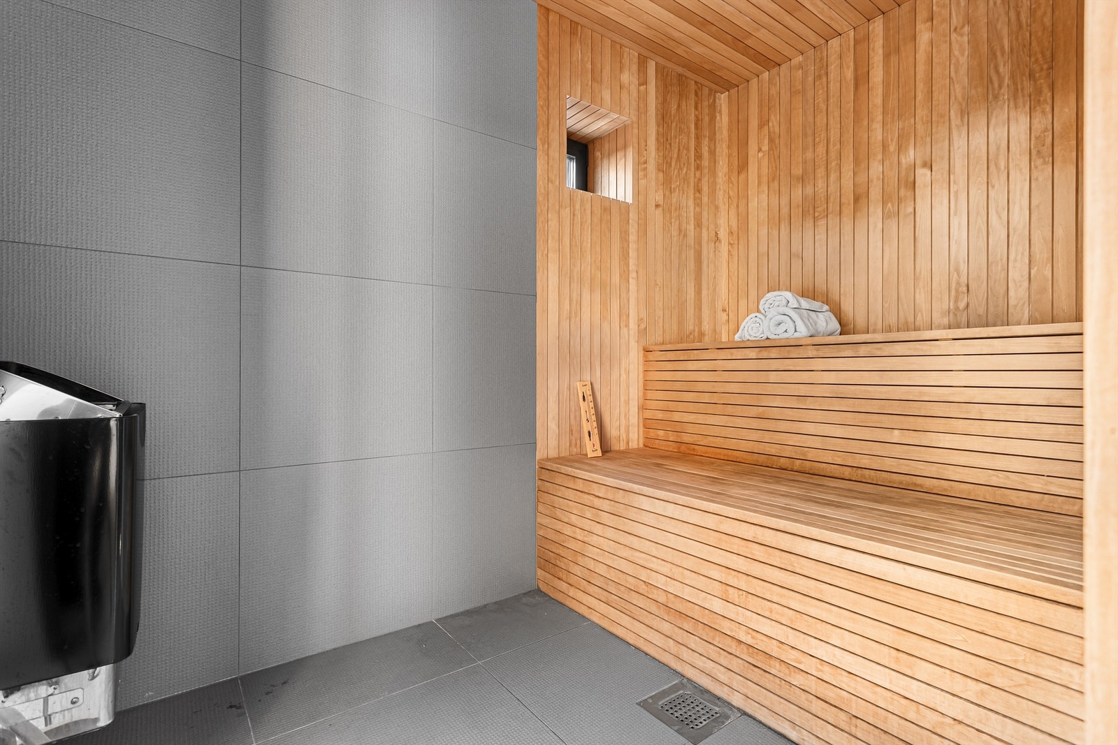 Badstue med plassbygde sittebenker i to nivåer og Harvia badstueovn Galleribilde