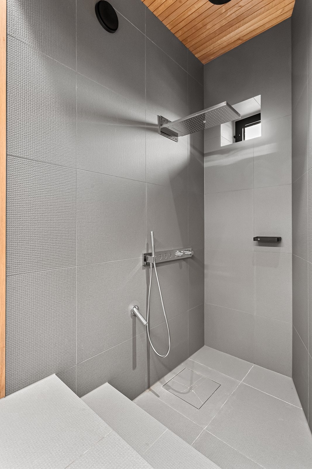 Bad 1 med dusjhjørne som har veggmontert armatur og regnfallsdusj Galleribilde