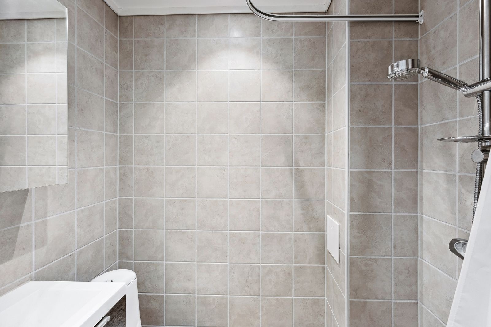 Leiligheten har et flislagt bad med wc, servantinnredning med underskap, speil, belysning og dusj. Galleribilde