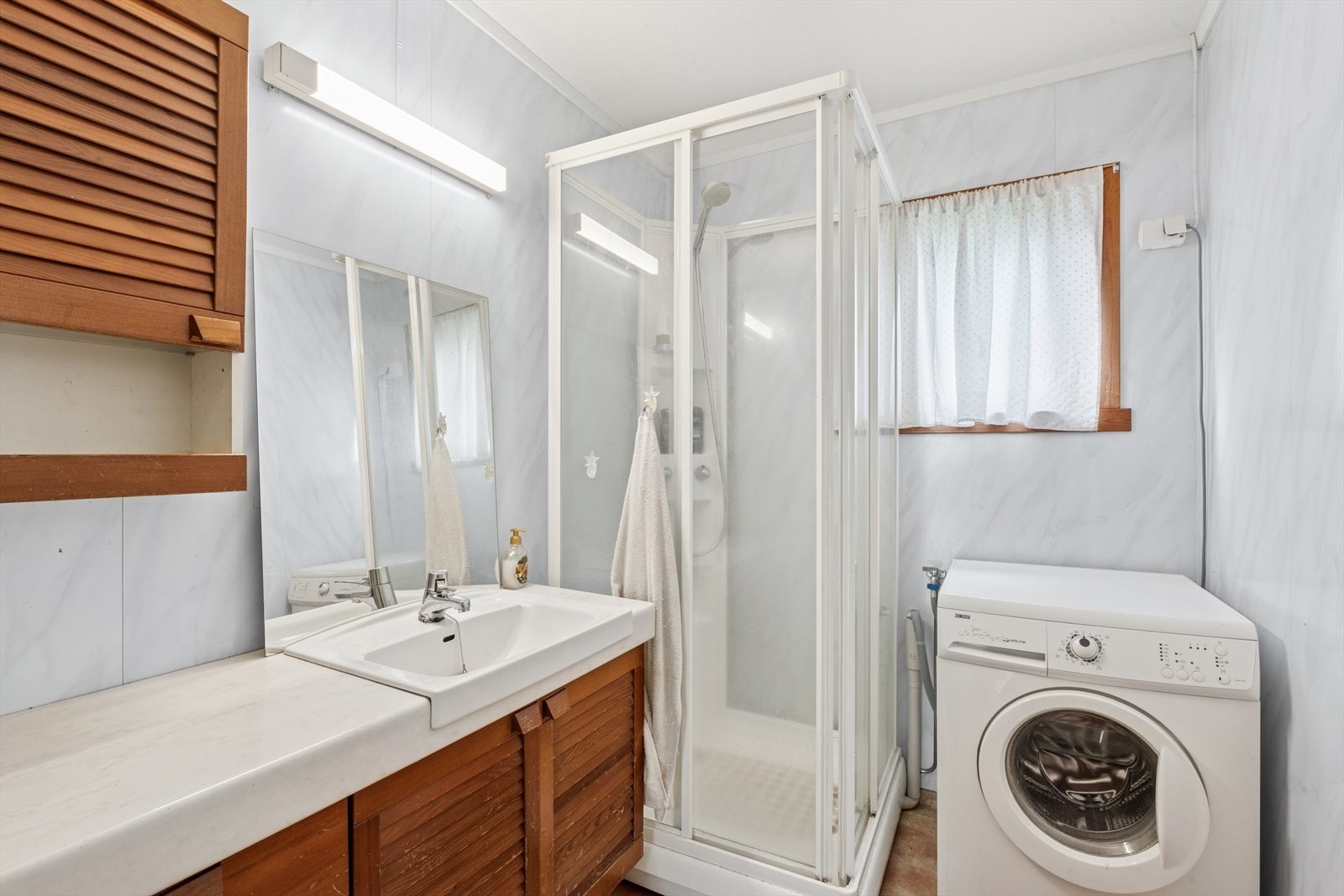 Badet er innredet med baderomsinnredning med servant, underskap, speil og lysarmatur. Gulvmontert toalett og dusjkabinett. Opplegg for vaskemaskin. Galleribilde