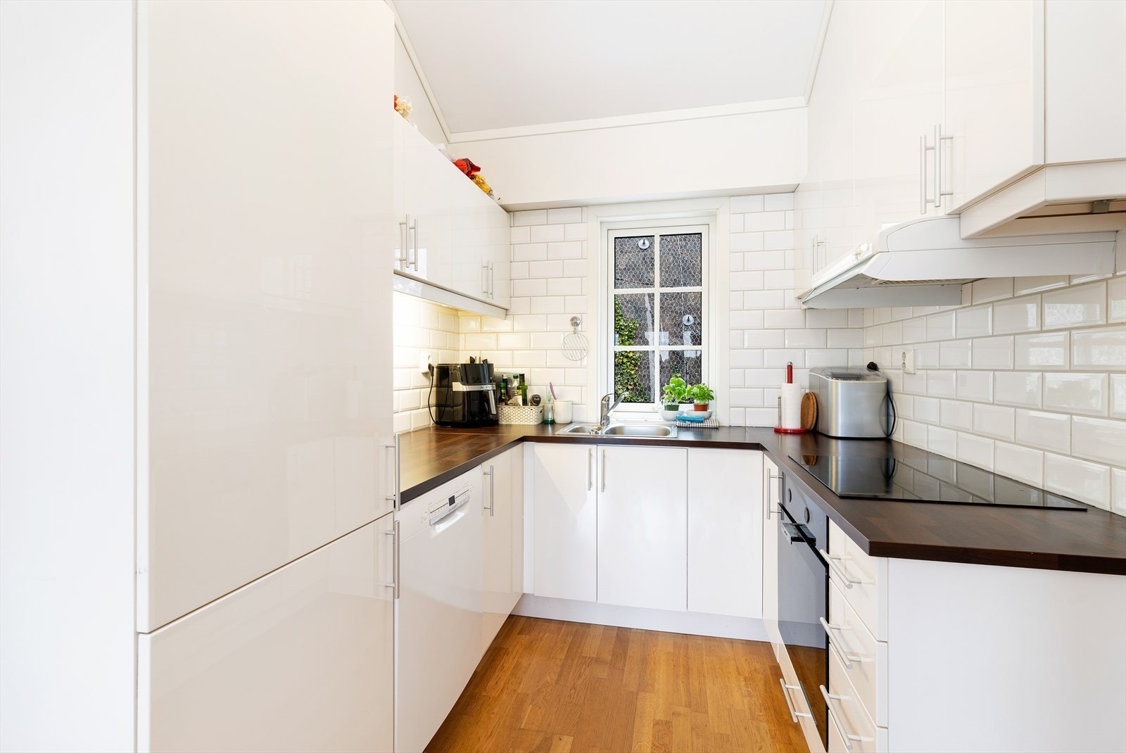 Kjøkken med hvite glatte fronter og heltre benkeplate. Hvitevarer medfølger salget. Galleribilde