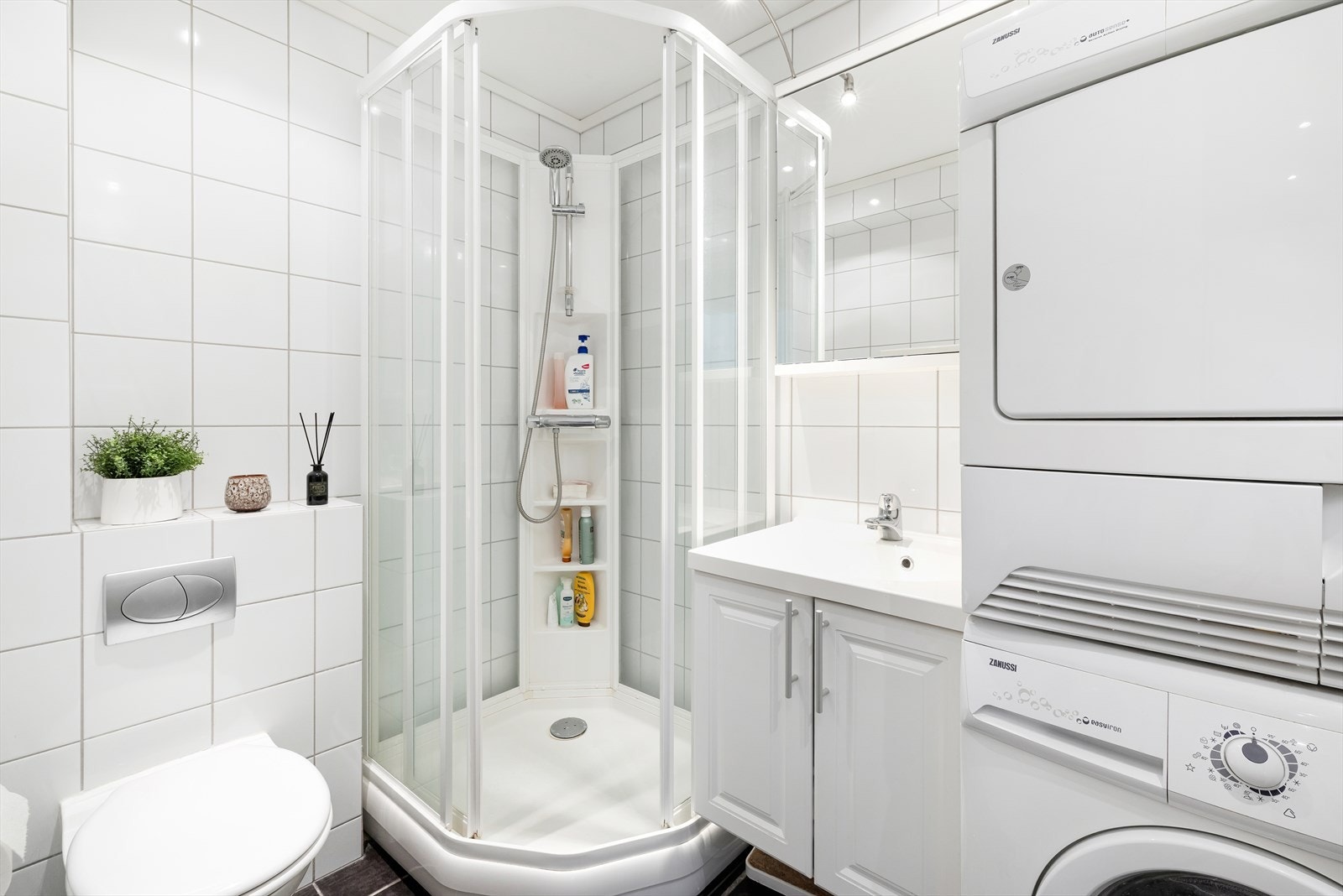 Flislagt bad med dusjkabinett, vegghengt toalett og servant med underskap. Opplegg til vask og tørkemaskin. Galleribilde