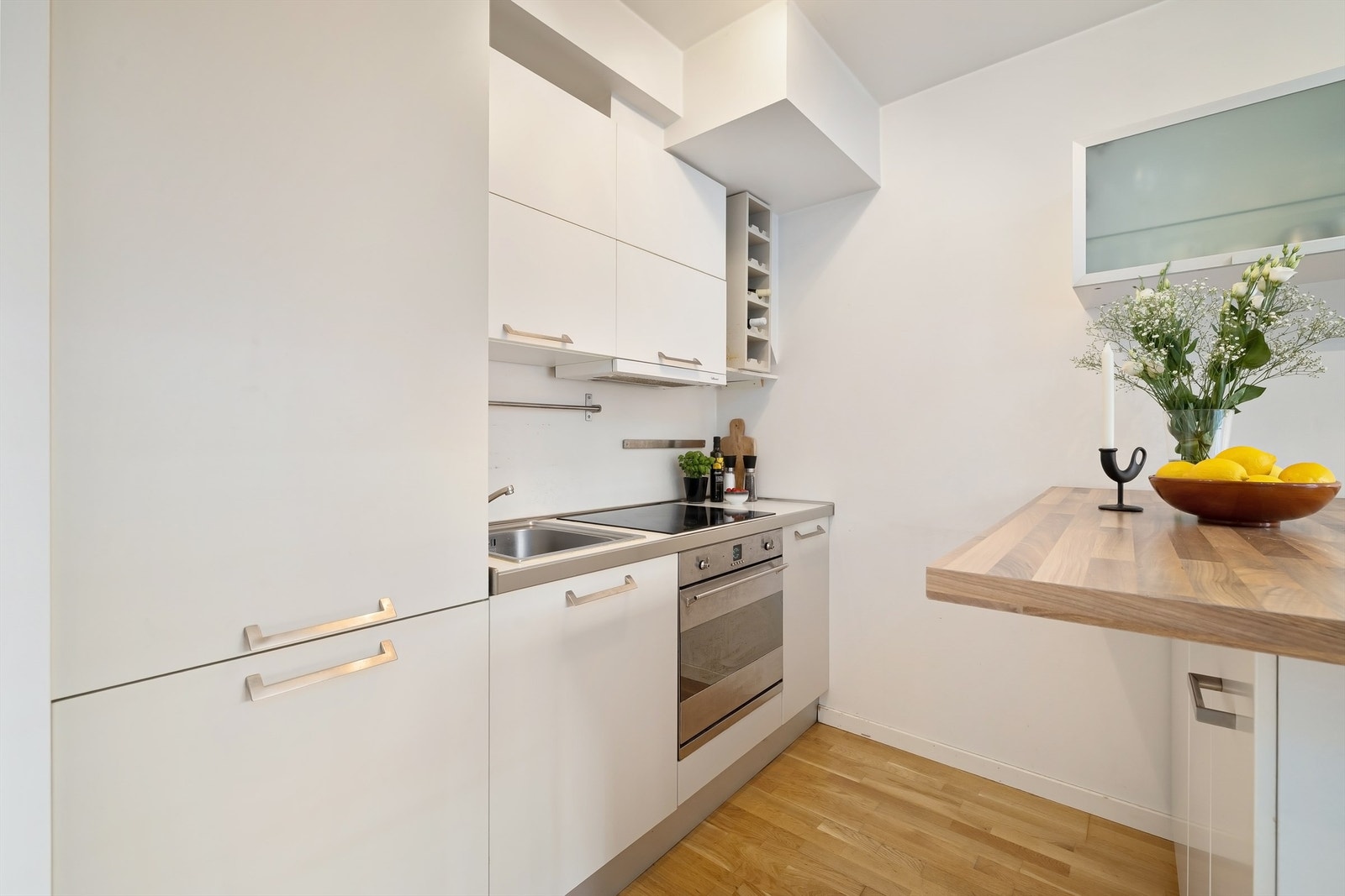 Kjøkkenet har integrerte hvitevarer som kjøleskap med frysedel, stekeovn og nedfelt platetopp med ventilator i overskap Galleribilde