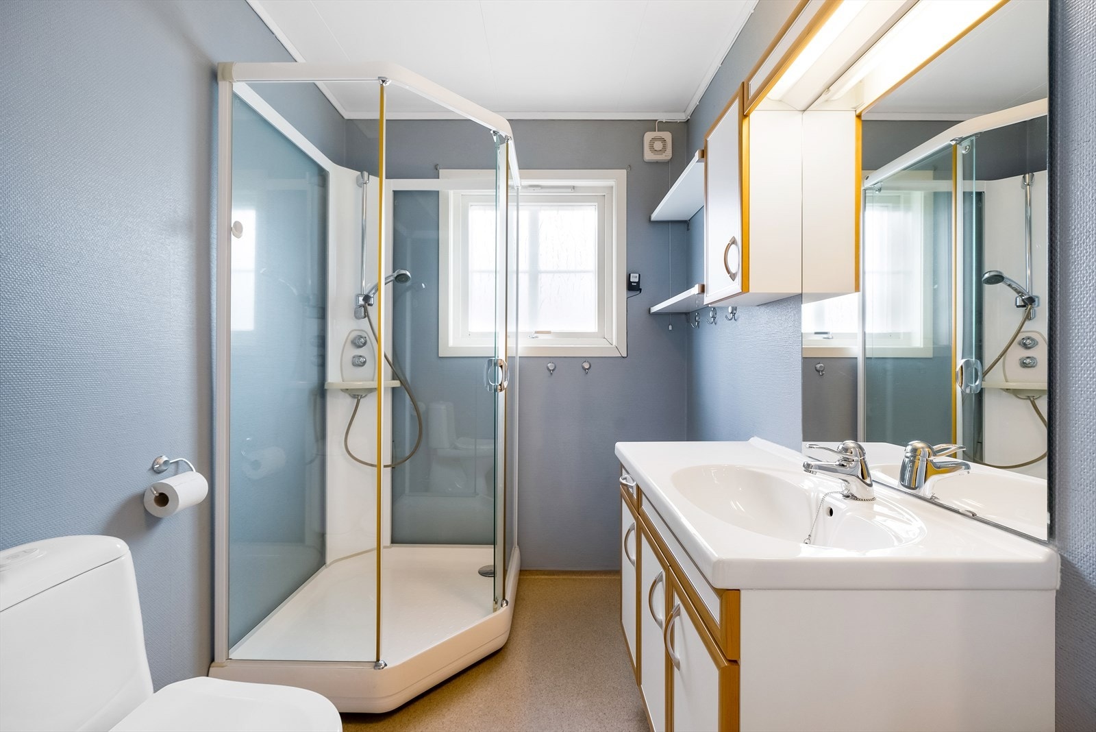 Badet i hovedetasjen har belegg på gulv og tapet på veggene. Rommet er innredet med baderomsinnredning, toalett og dusjkabinett. Galleribilde