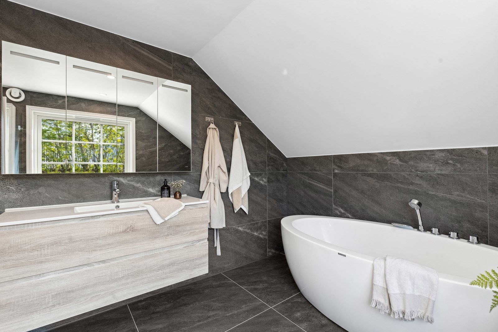 Det er innredning med nedfelt servant, veggmontert toalett, badekar og dusjvegger/hjørne Galleribilde