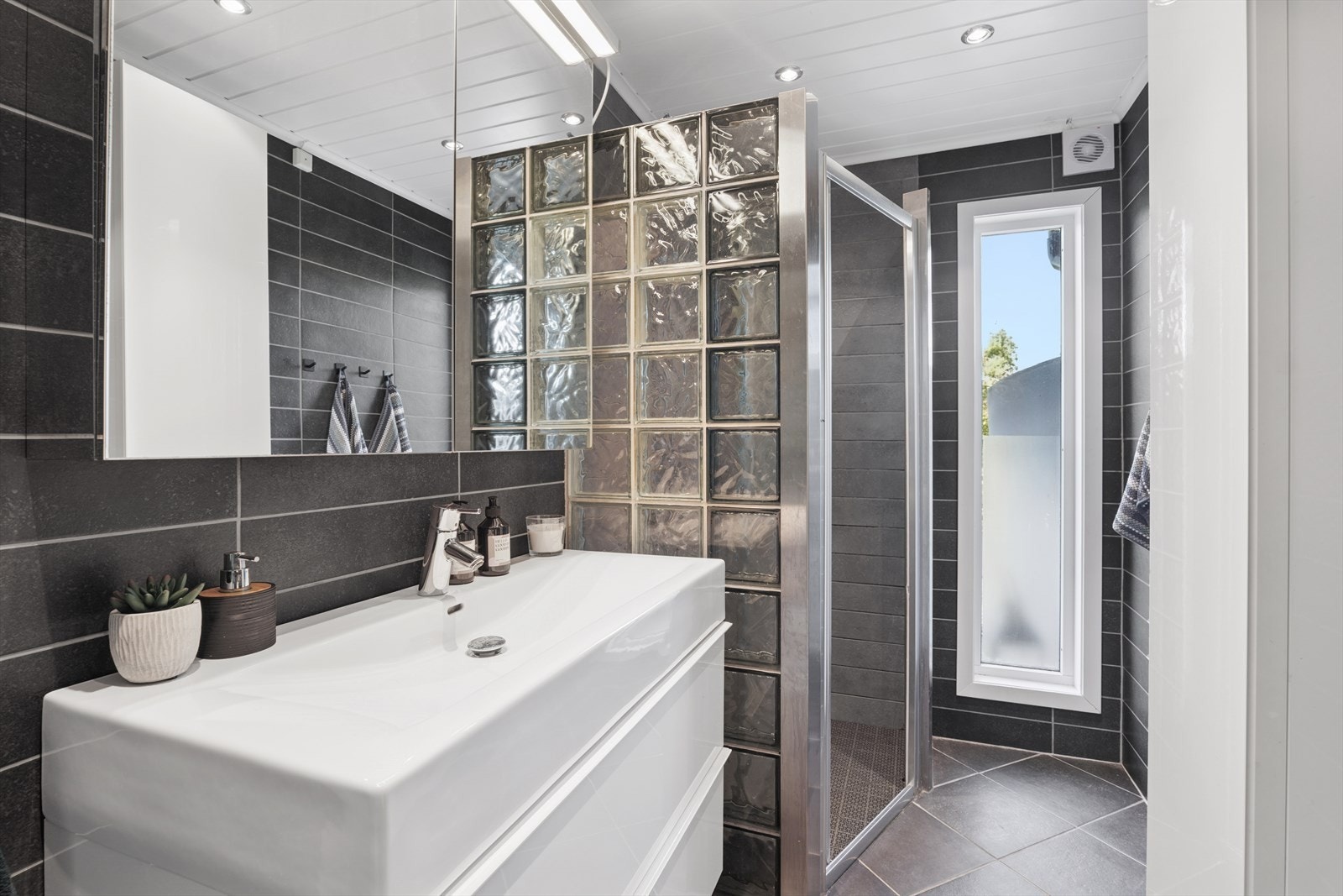 Badet er utstyrt med dusjhjørne, toalett og en lys og moderne baderomsinnredning. Galleribilde