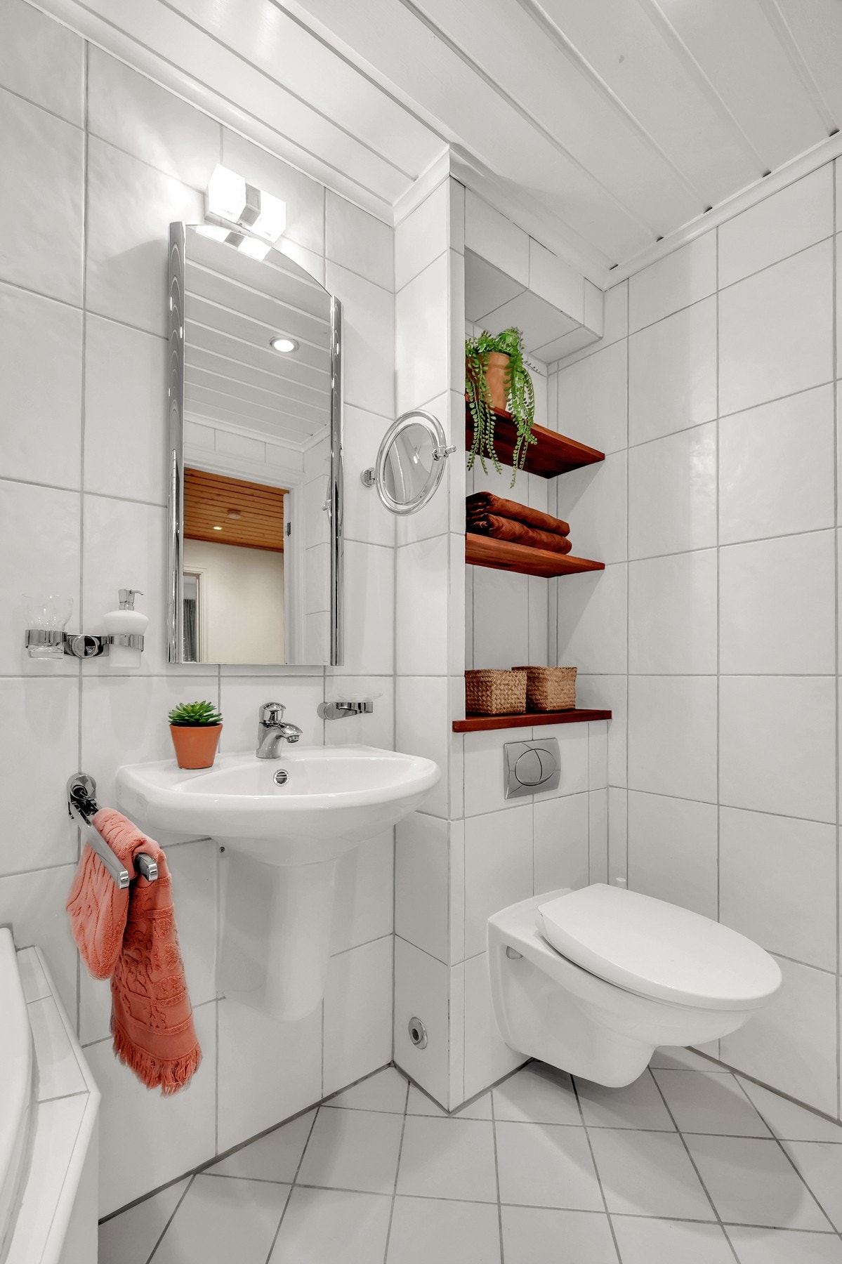 Videre inneholder badet vegghengt toalett med plassbygde hyller på vegg ovenfor. Galleribilde