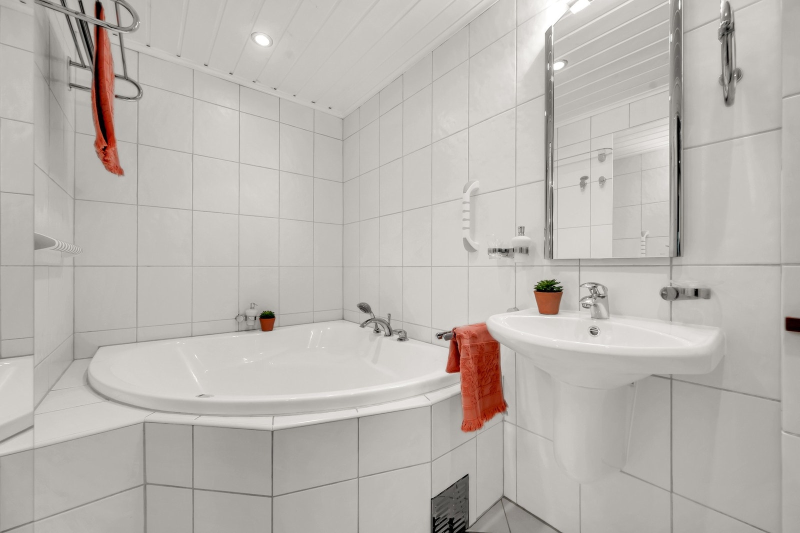 Badet har vegghengt servant og speil med overbelysning på vegg over servant. Galleribilde