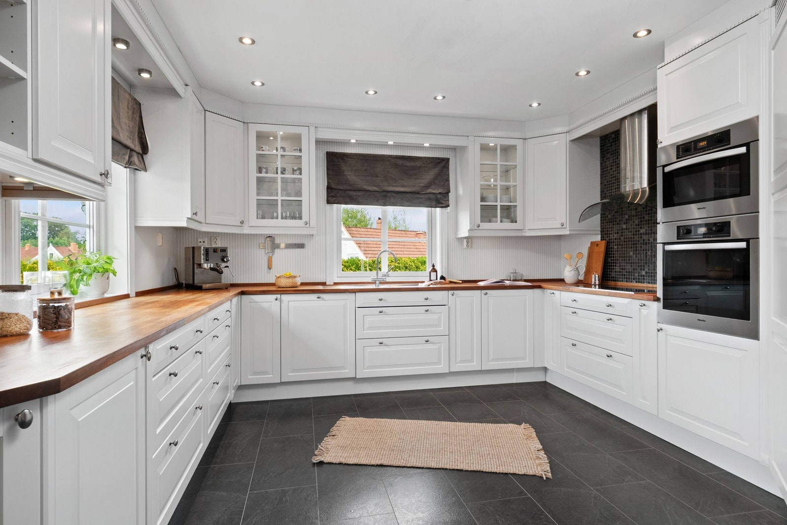 Innredningen har hvite, profilerte fronter, vitrinedører, takhøye skap og solid benkeplate i heltre med underlimt kum i stål. Galleribilde