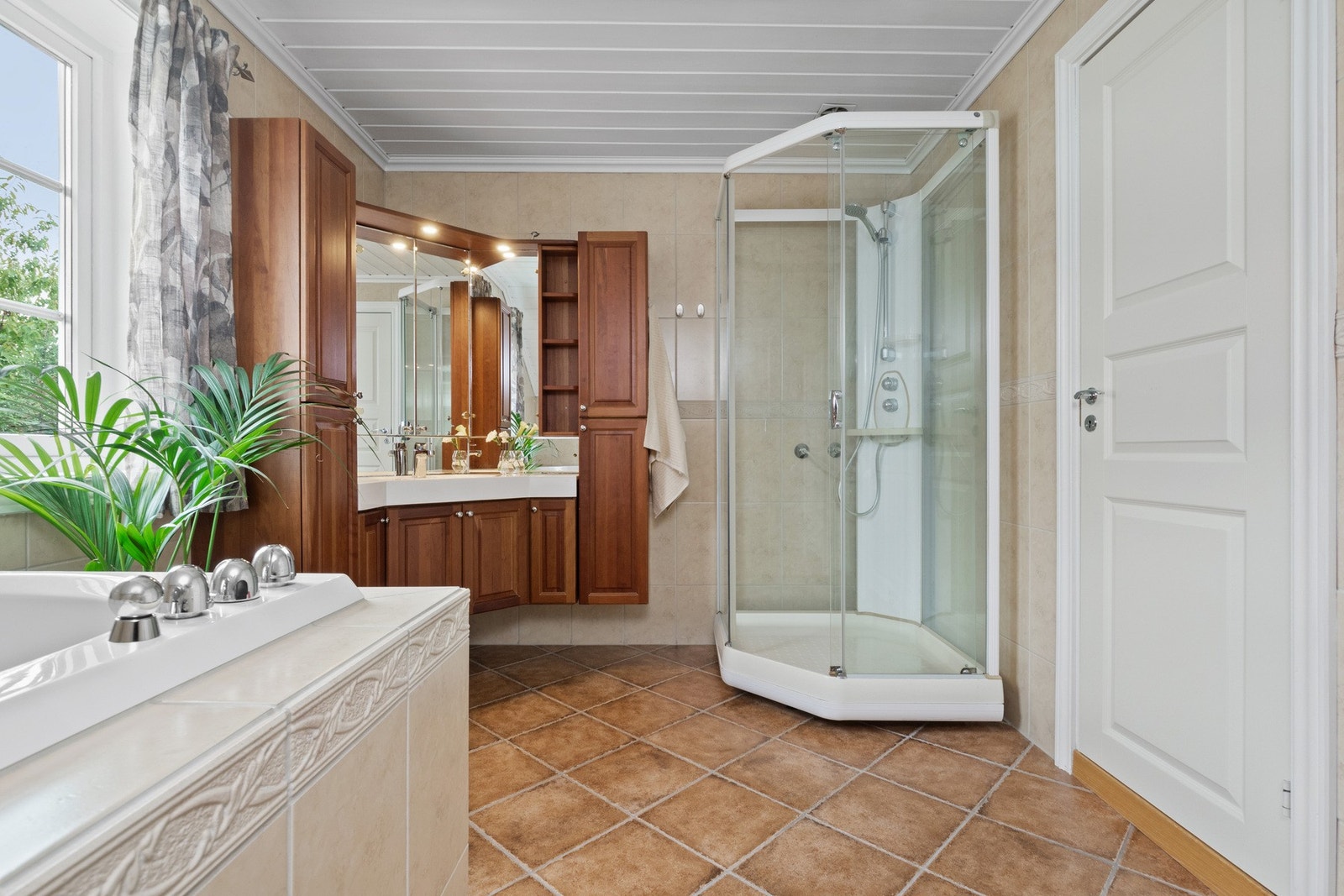 Badet ligger ved soverommene i andre etasje, og har lyse fliser på veggene og jordfargede fliser på gulv med gulvvarme. Galleribilde