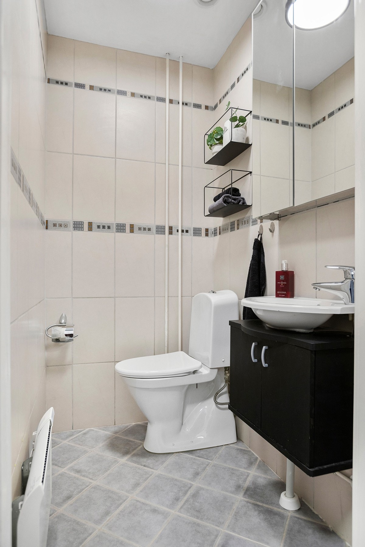 Separat toalettrom med fliser, gulvmontert toalett, servantskap og speilskap. Galleribilde