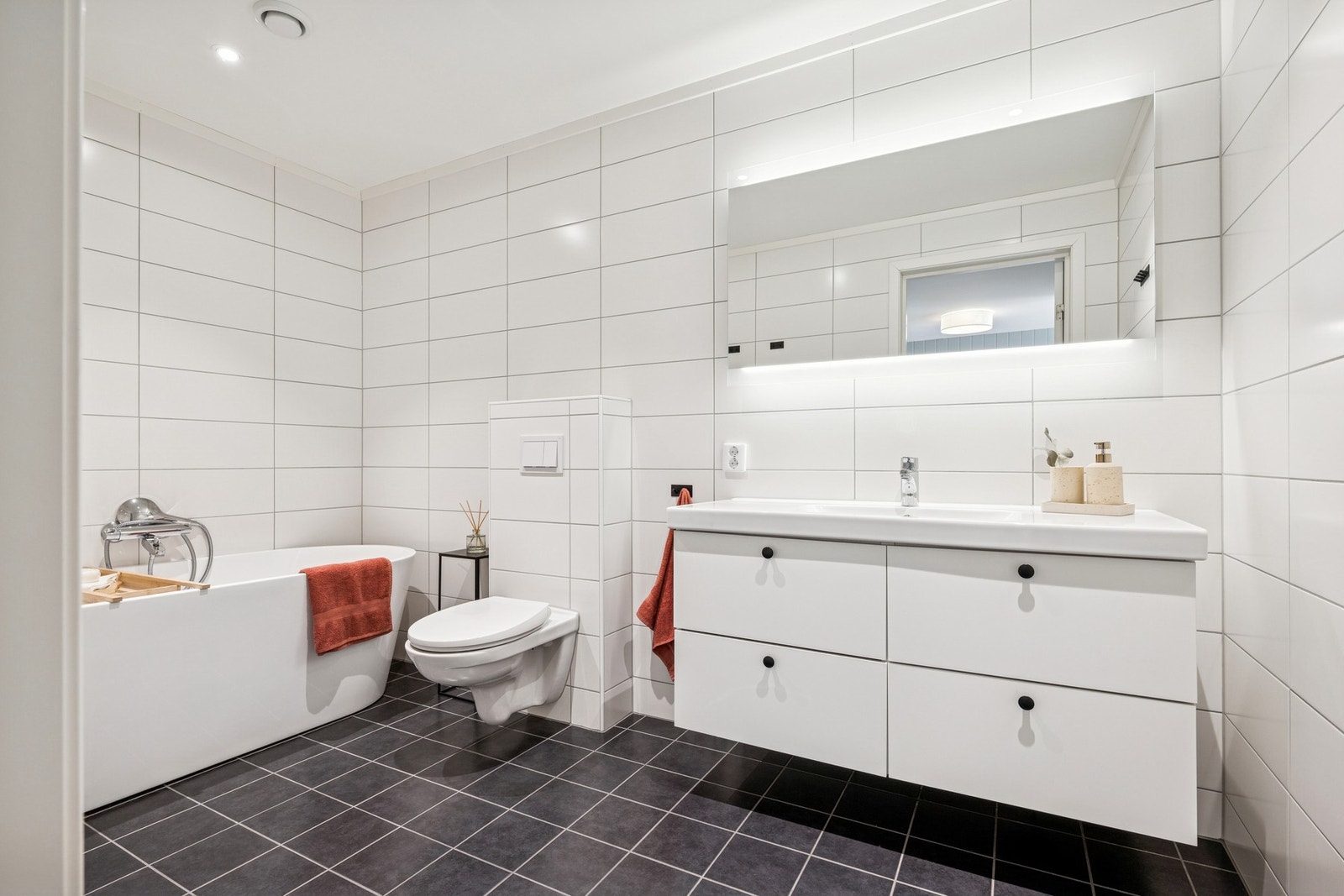 Et lyst og delikat baderom utstyrt med servantinnredning, toalett og badekar. Galleribilde