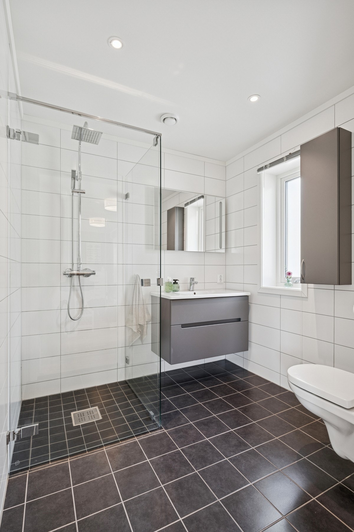 Lekkert bad utstyrt med dusjhjørne, servantinnredning og toalett. Galleribilde