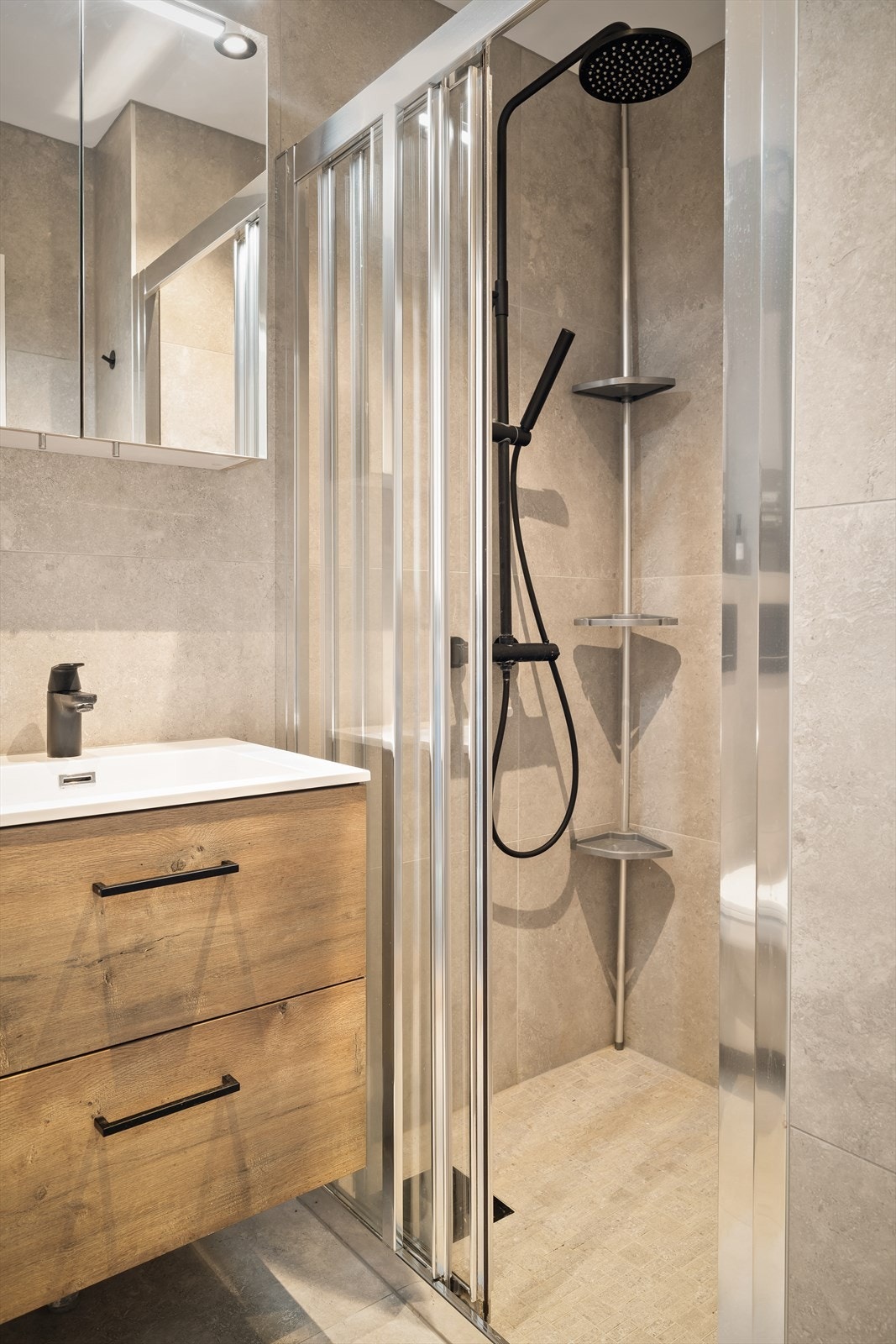 Badets areal er velutnyttet med romslig dusjnisje avskjermet med skyvedører, utstyrt med både hånd- og regndusj. Galleribilde