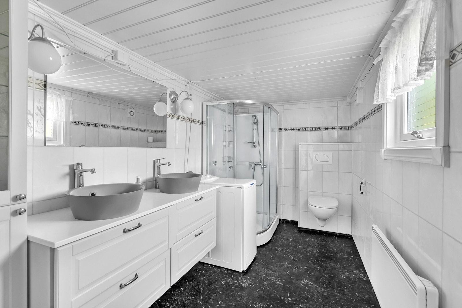 Badet har gulv med belegg og vegger kledd med våtromsplater. Galleribilde