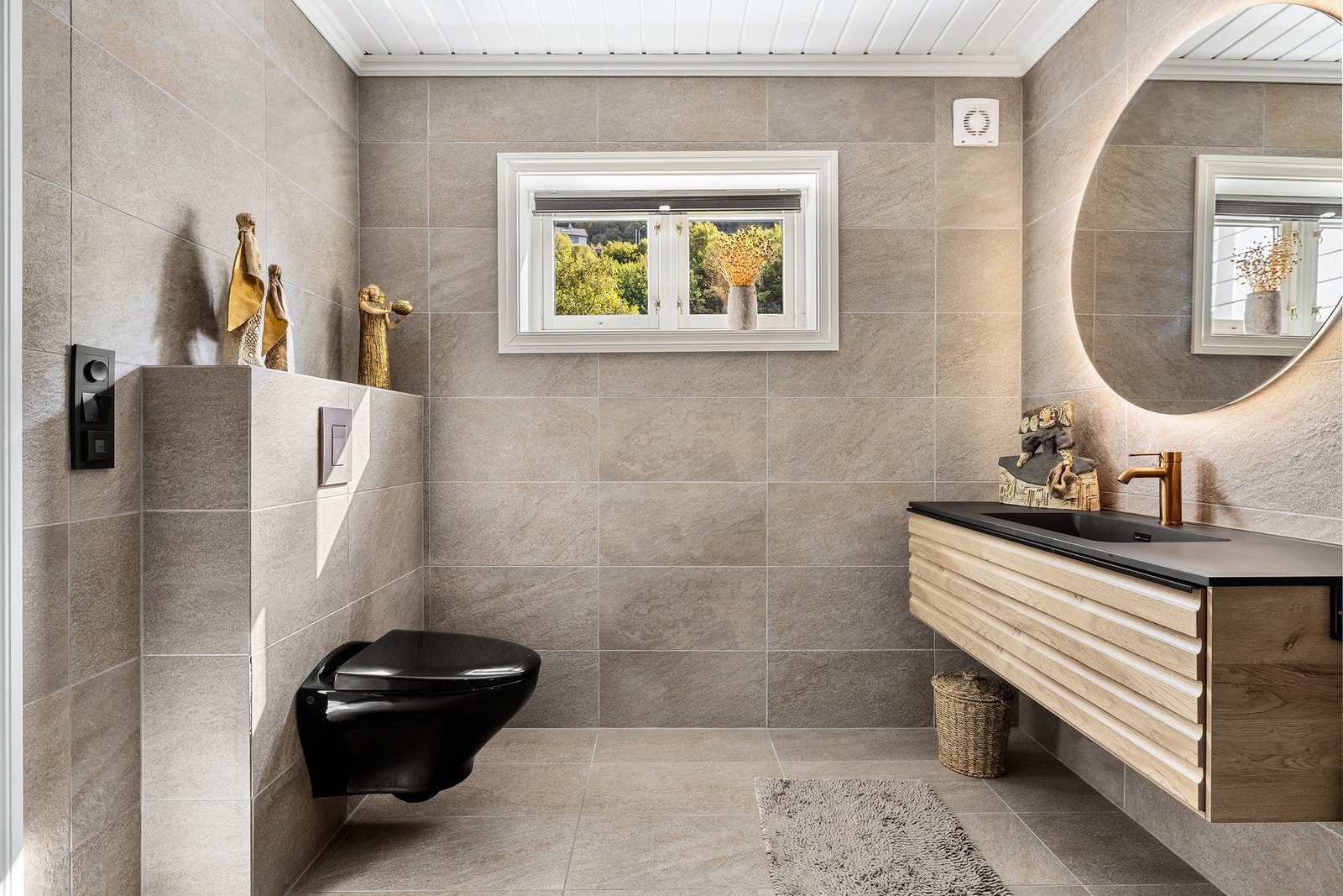 Det er innredet med vegghengt toalett, dusj med glassvegger og baderomsinnredning med servant, speil og belysning. Galleribilde