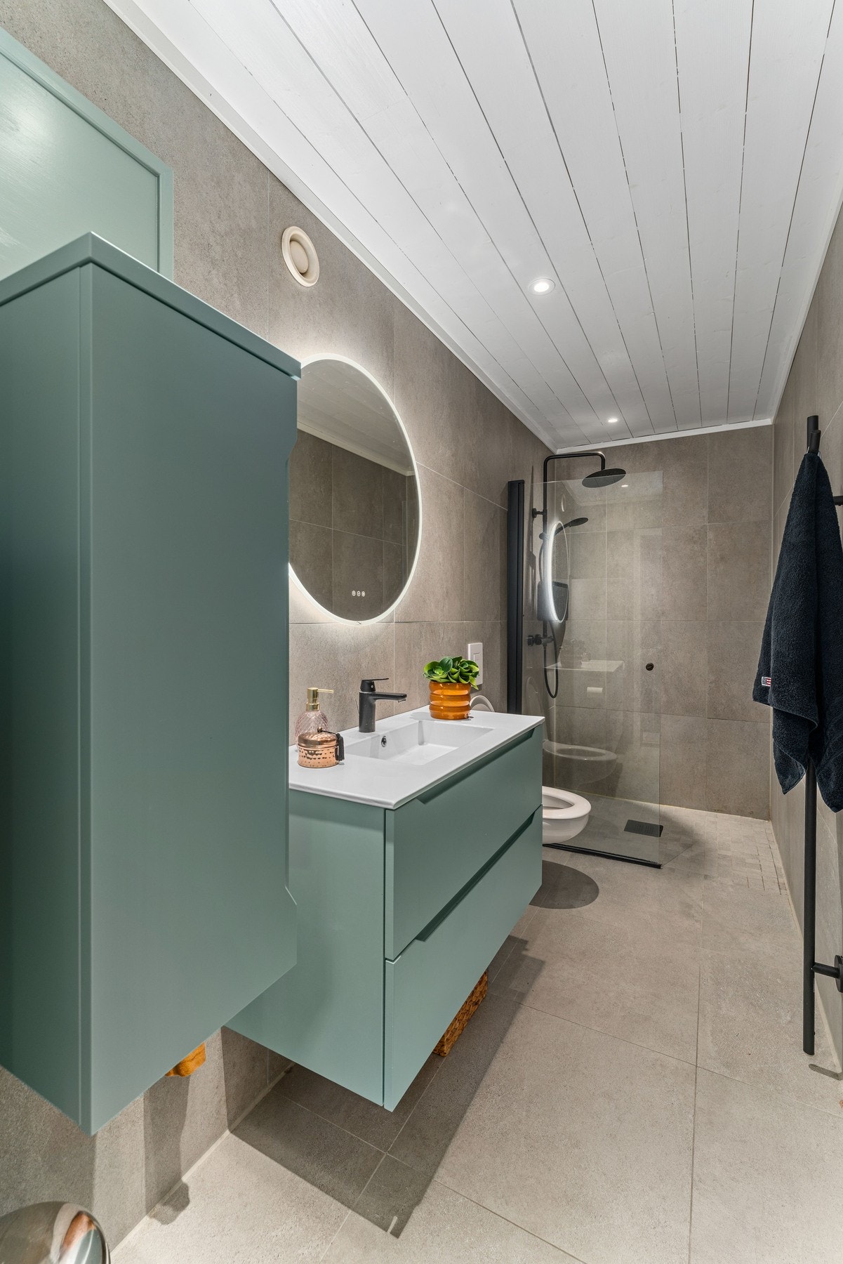 Baderommet i 1. etasje er smakfullt oppgradert med tidløse materialvalg. Badet er utstyrt med vegghengt servantskap med skuffer, dusjhjørne med glassdører og regndusj i sort utførelse, samt vegghengt toalett. Galleribilde